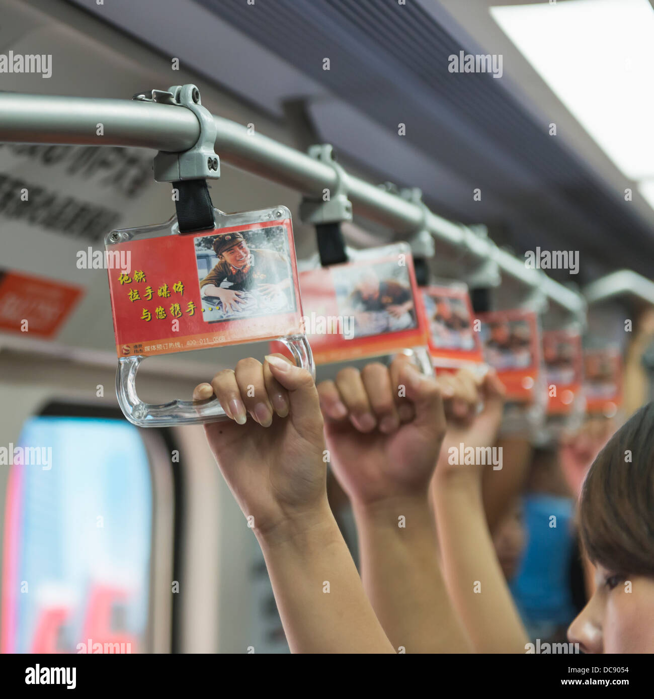 I passeggeri dei mezzi di trasporto pubblici tenere su maniglie mentre equitazione; Pechino, Cina Foto Stock