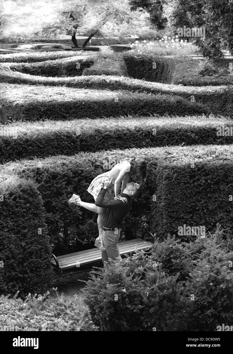 Giovane donna attraente saltando nel suo fidanzato bracci dopo essendo impegnato in un giardino labirinto Foto Stock