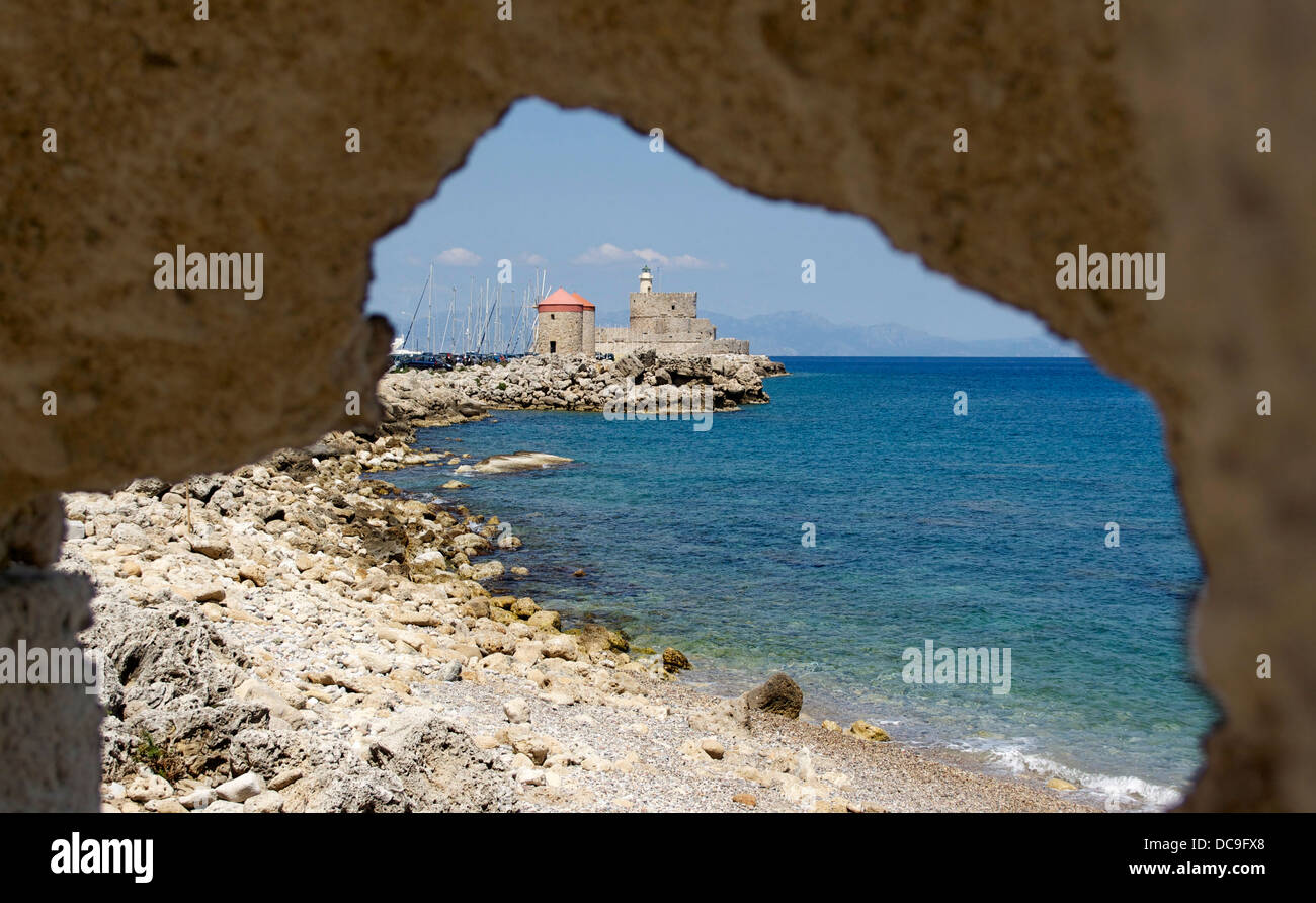 Vecchio porto di Rodi, Grecia, attraverso un foro nel le mura medievali della città. Le coste turche presso Horizon Foto Stock
