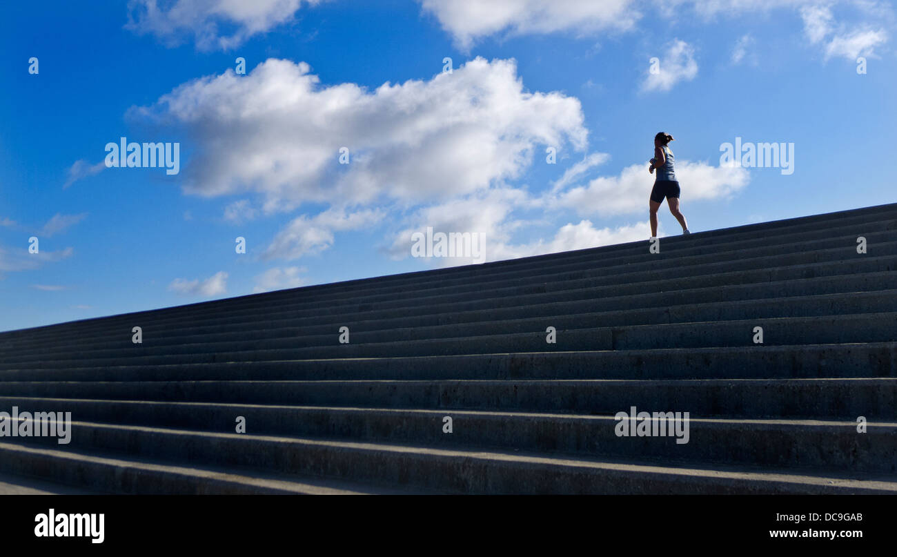 Donna che corre lungo la parte superiore di una parete del mare. Foto Stock