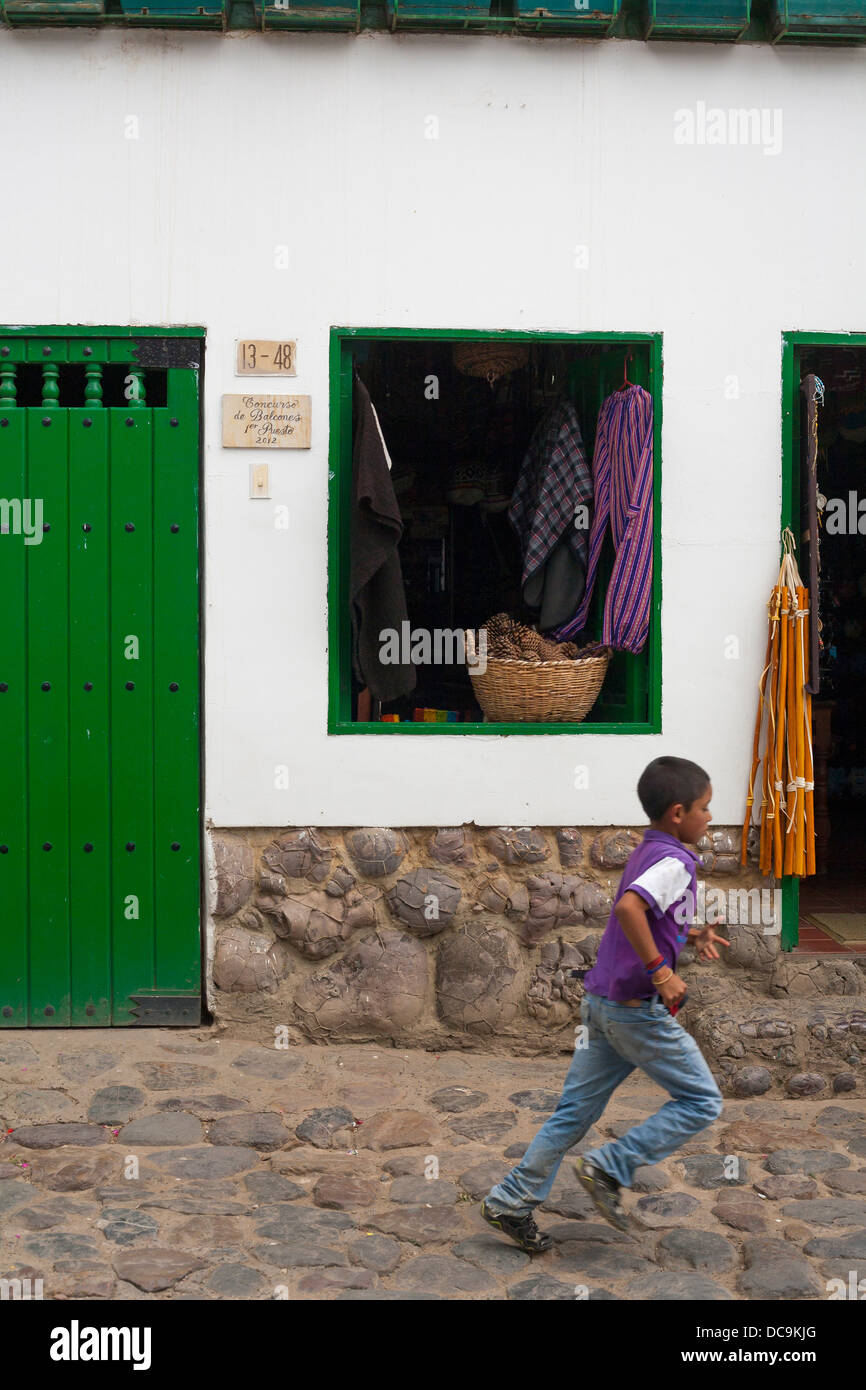 Un ragazzo corre passato l'architettura coloniale nelle strade di Villa de Leyva nel Boyaca Distretto di Colombia Foto Stock