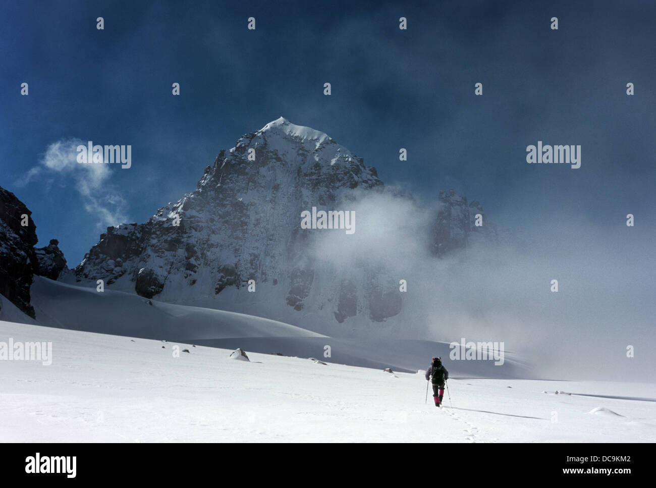 Vista posteriore del montanaro passeggiate sulla neve glacier nel paesaggio di montagna. singolo picco in background. chiaro cielo di nuvole basse. asia Foto Stock