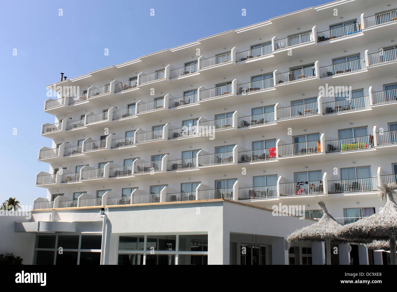 Spagnolo bianco edificio alberghiero con ombrelloni in primo piano. Foto Stock