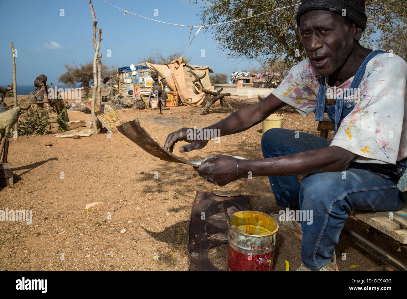Artista Amadou Dieng dimostrando come lavora con trovato e recuperato oggetti per rendere le sue costruzioni. Isola di Goree Senegal. Foto Stock