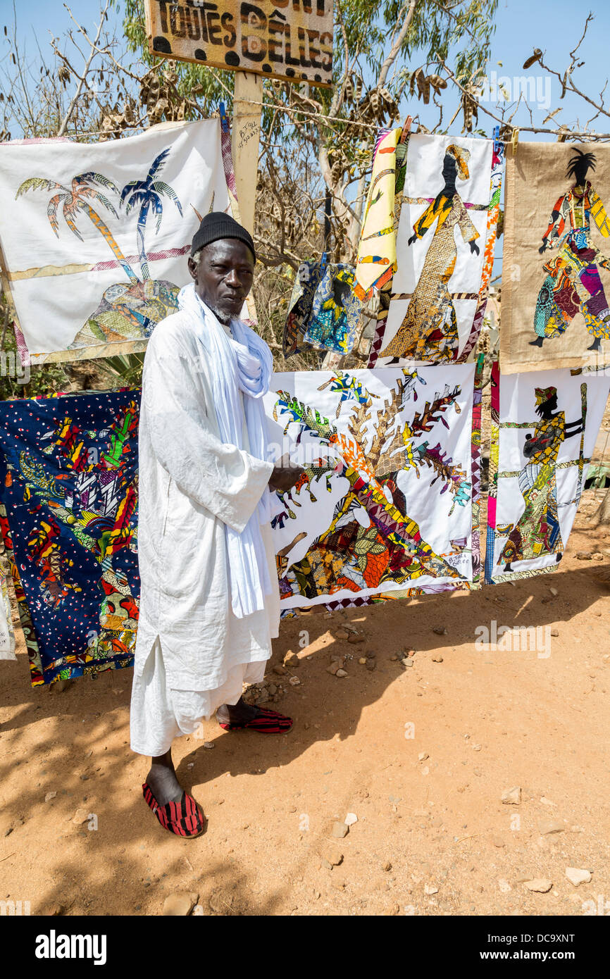 Tessuto artista Bara caduta e le sue creazioni, isola di Goree, Senegal. Egli sta usando un bastone da masticare, per mantenere i suoi denti puliti. Foto Stock