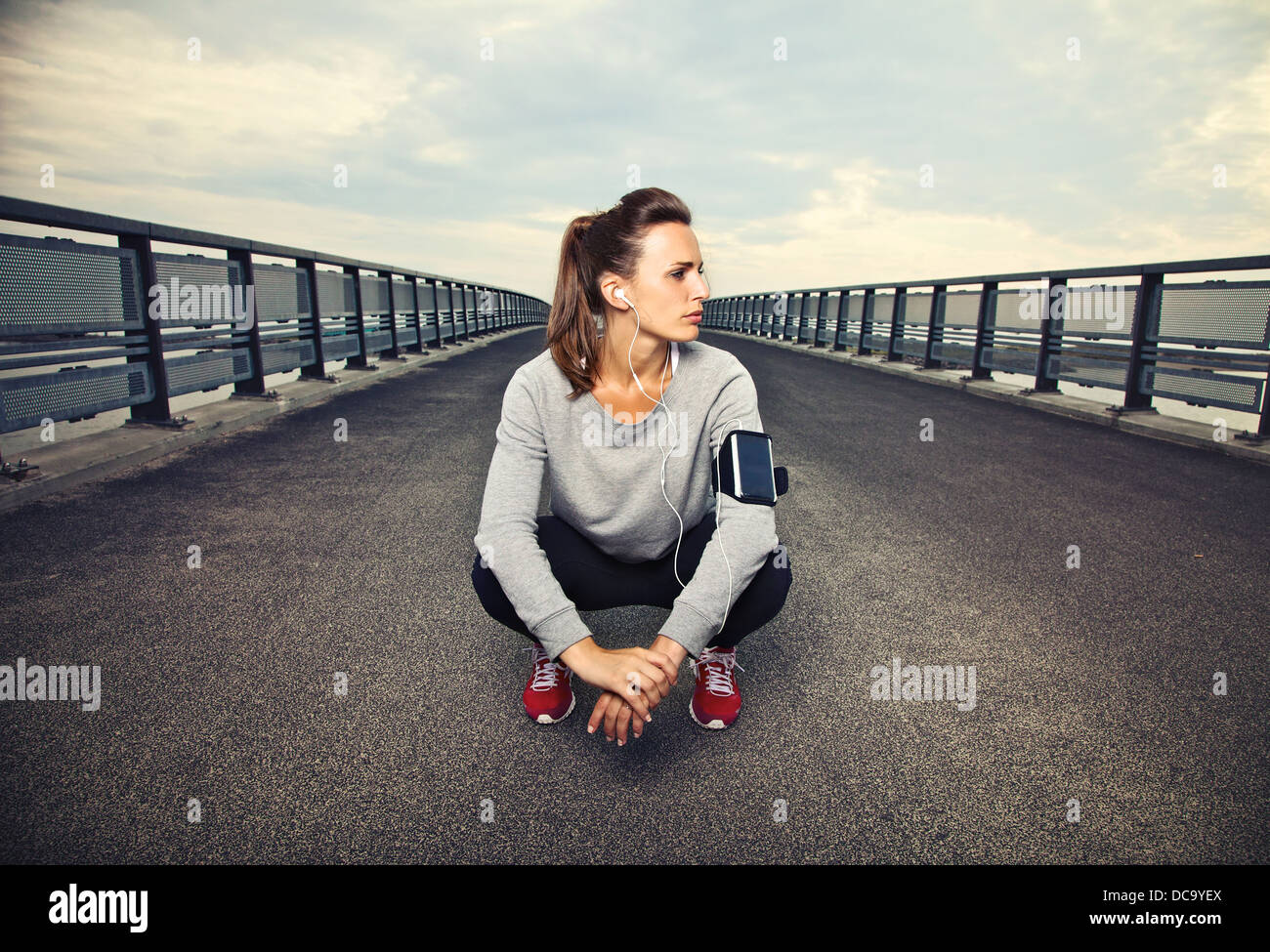 Runner donna seduta sul ponte dopo l'esecuzione Foto Stock