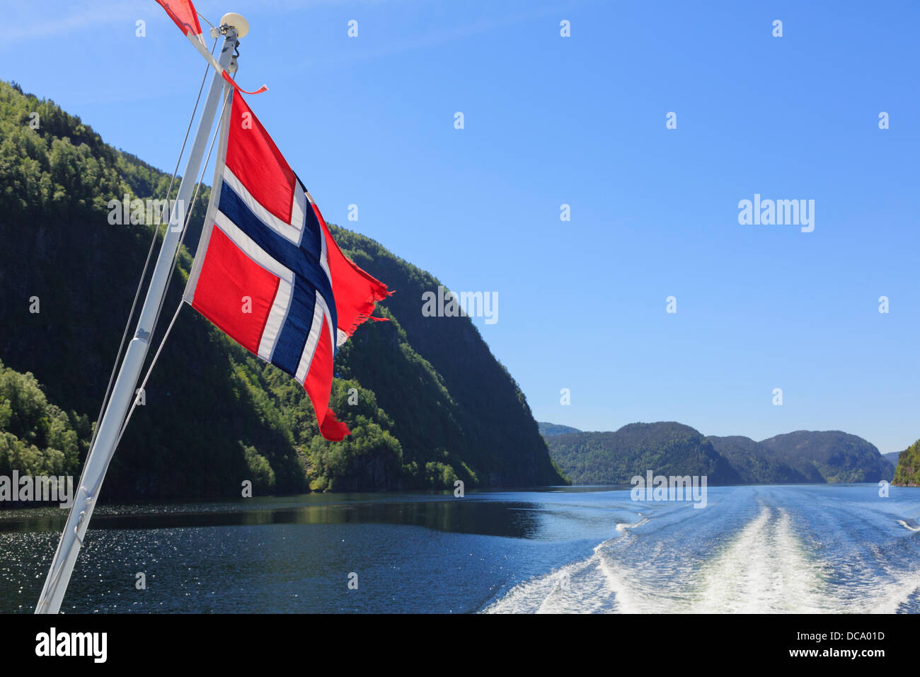 Bandiera norvegese a volare su un fiordo di barca a vela di crociera lungo Osterfjorden, Nordhordland, Hordaland, Norvegia e Scandinavia Foto Stock
