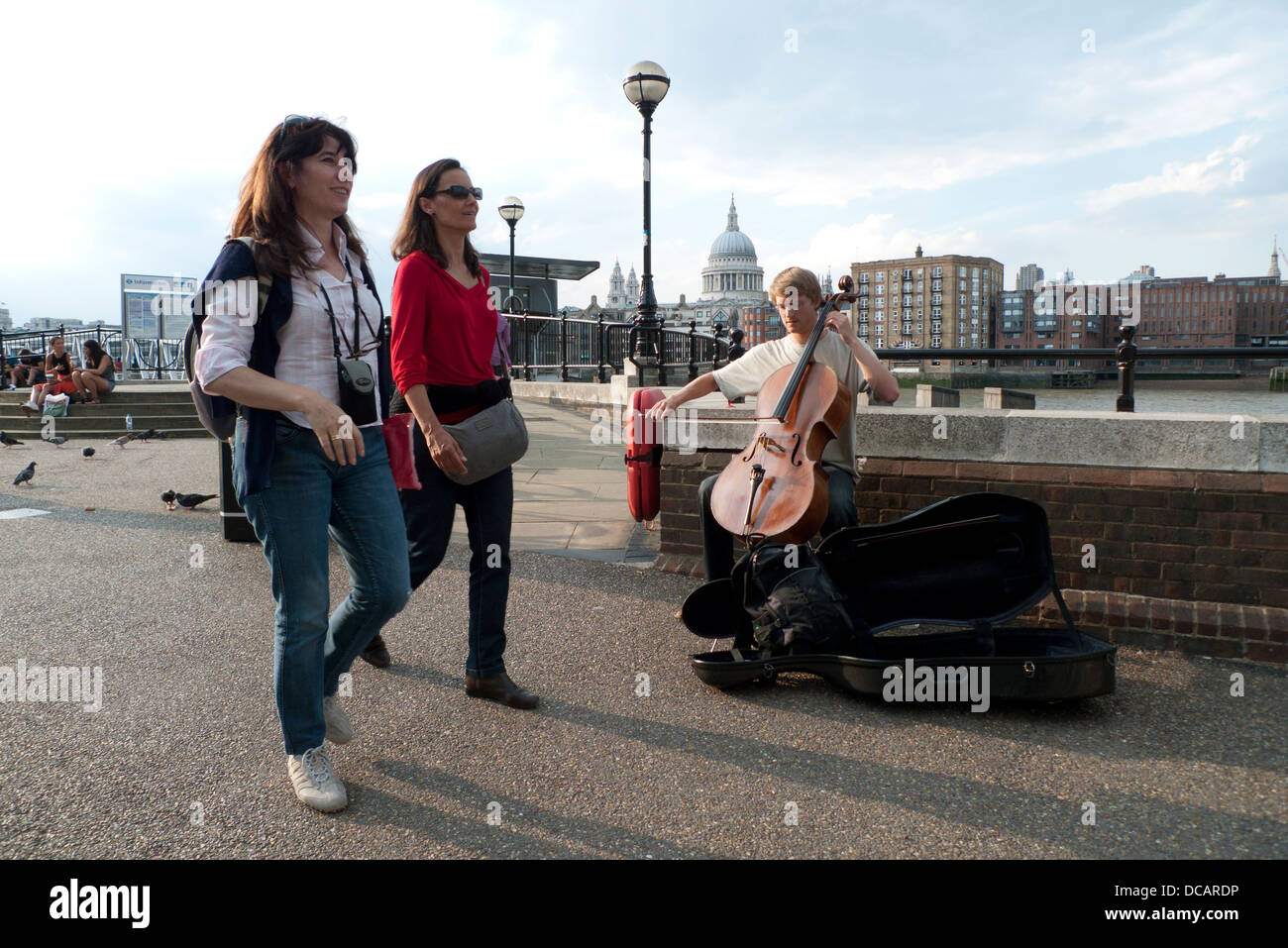 Un giovane uomo busker suonare la musica classica al violoncello con una vista della Cattedrale di San Paolo Southbank Londra UK KATHY DEWITT Foto Stock