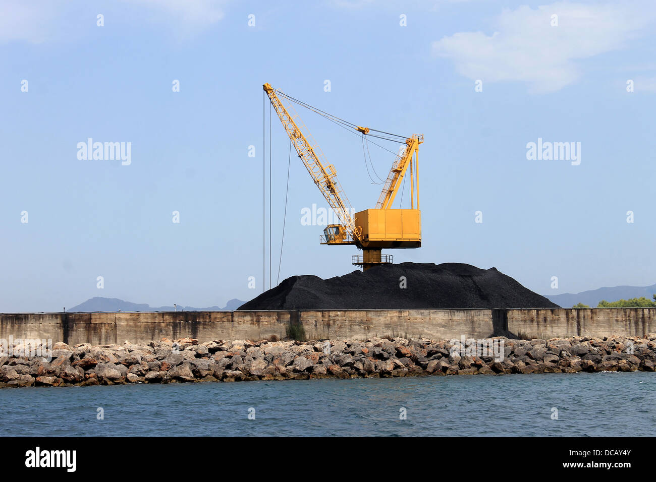Vista panoramica del giallo gru industriali e la pila di carbone sul dock, Porto di Alcudia, Maiorca, Spagna. Foto Stock