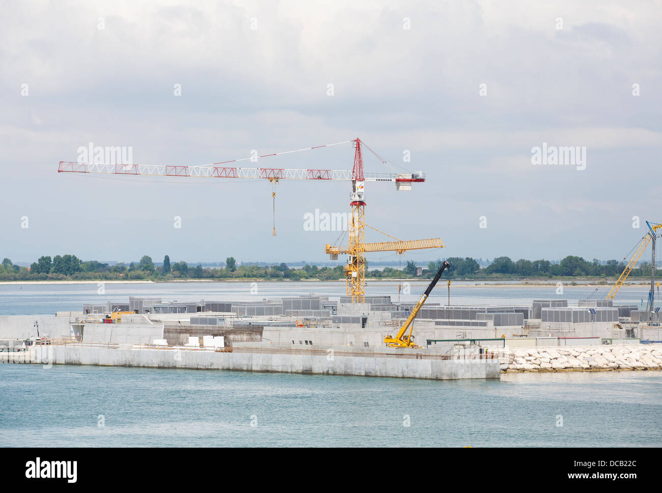 Giallo, rosso e bianco di gru di costruzione su un sito in un canale vicino a Venezia, Italia Foto Stock