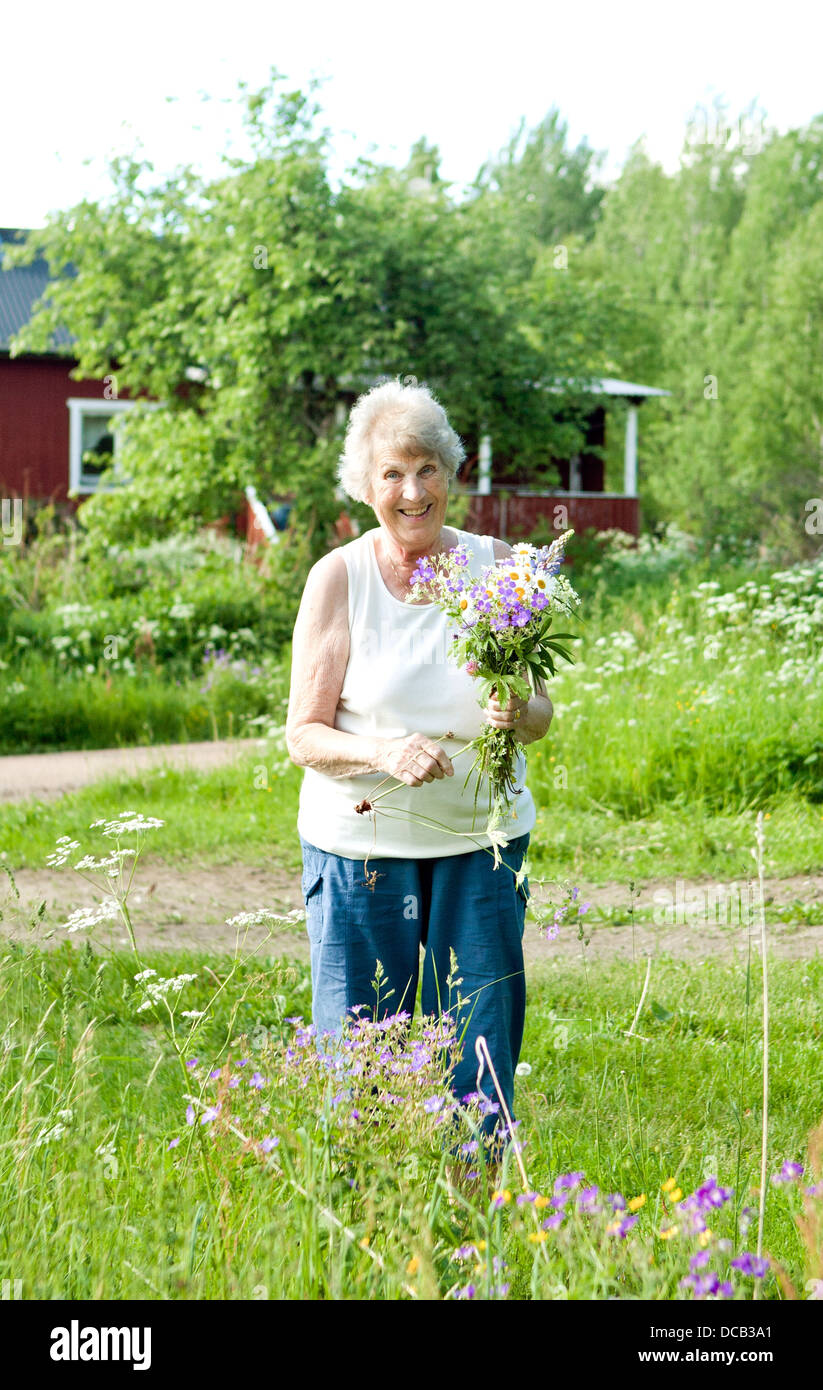 Sorridente donna senior a caccia di fiori Foto Stock
