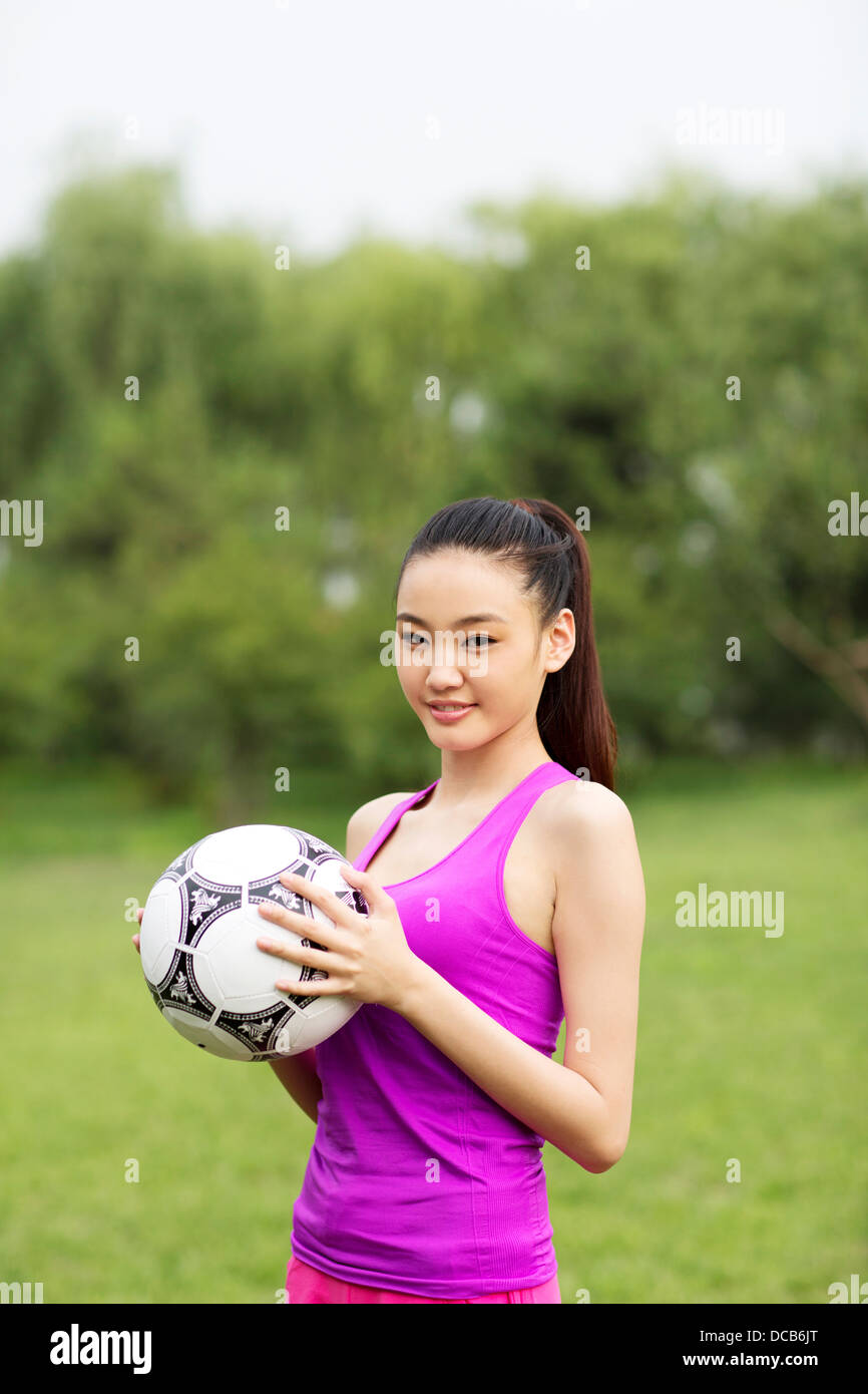 Giovane donna tenendo un calcio Foto Stock