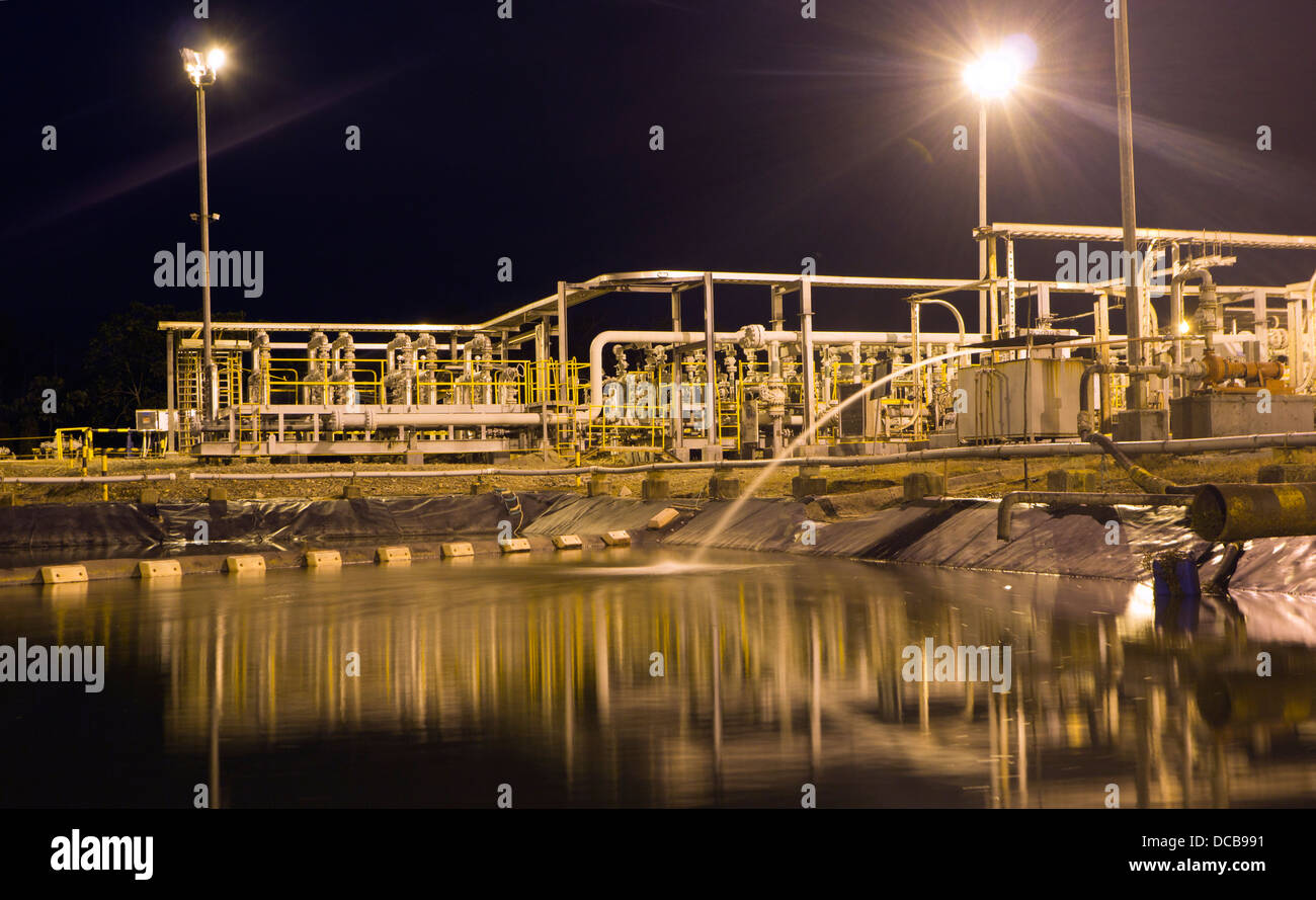 La piscina di acqua di produzione accanto a un pozzo di petrolio in Amazzonia ecuadoriana. Illumonated di notte. Foto Stock