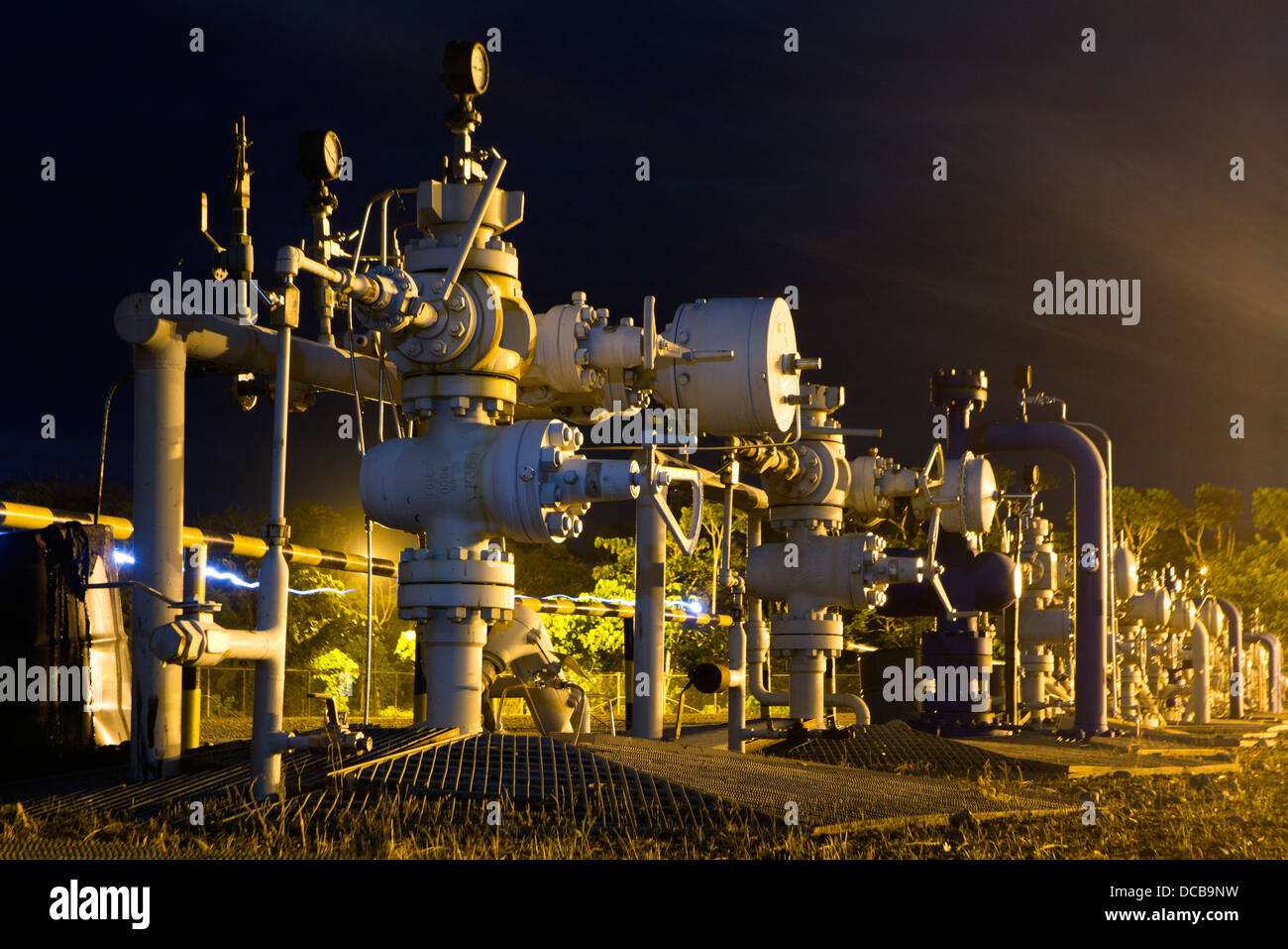 Fila di albero di Natale valvole su un pozzo di petrolio piattaforma nell'Amazzonia ecuadoriana illuminata di notte Foto Stock