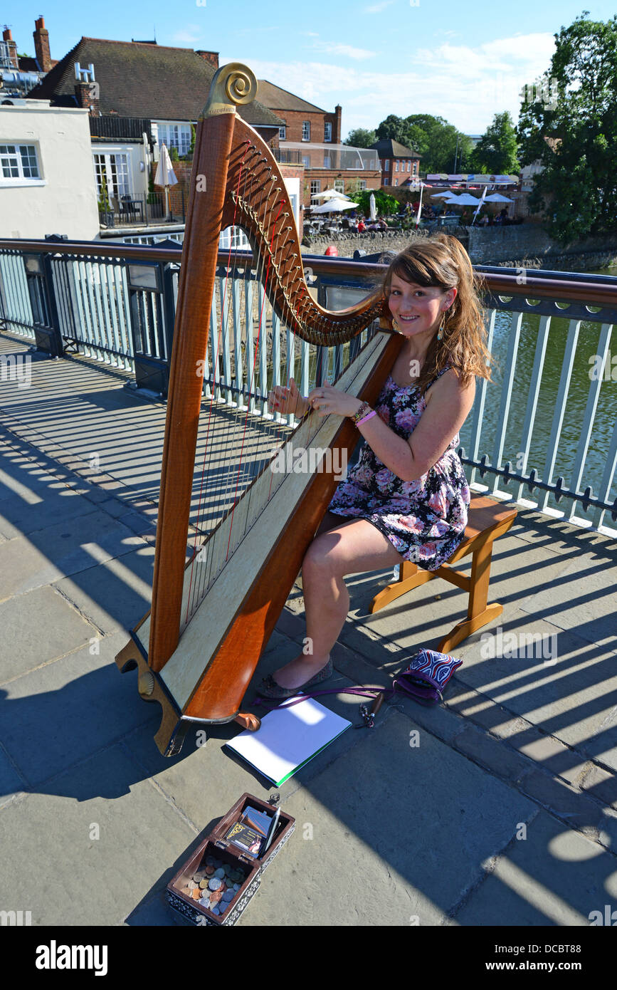 Giovani femmine busker suona l'arpa sul ponte di Windsor, Windsor, Berkshire, Inghilterra, Regno Unito Foto Stock