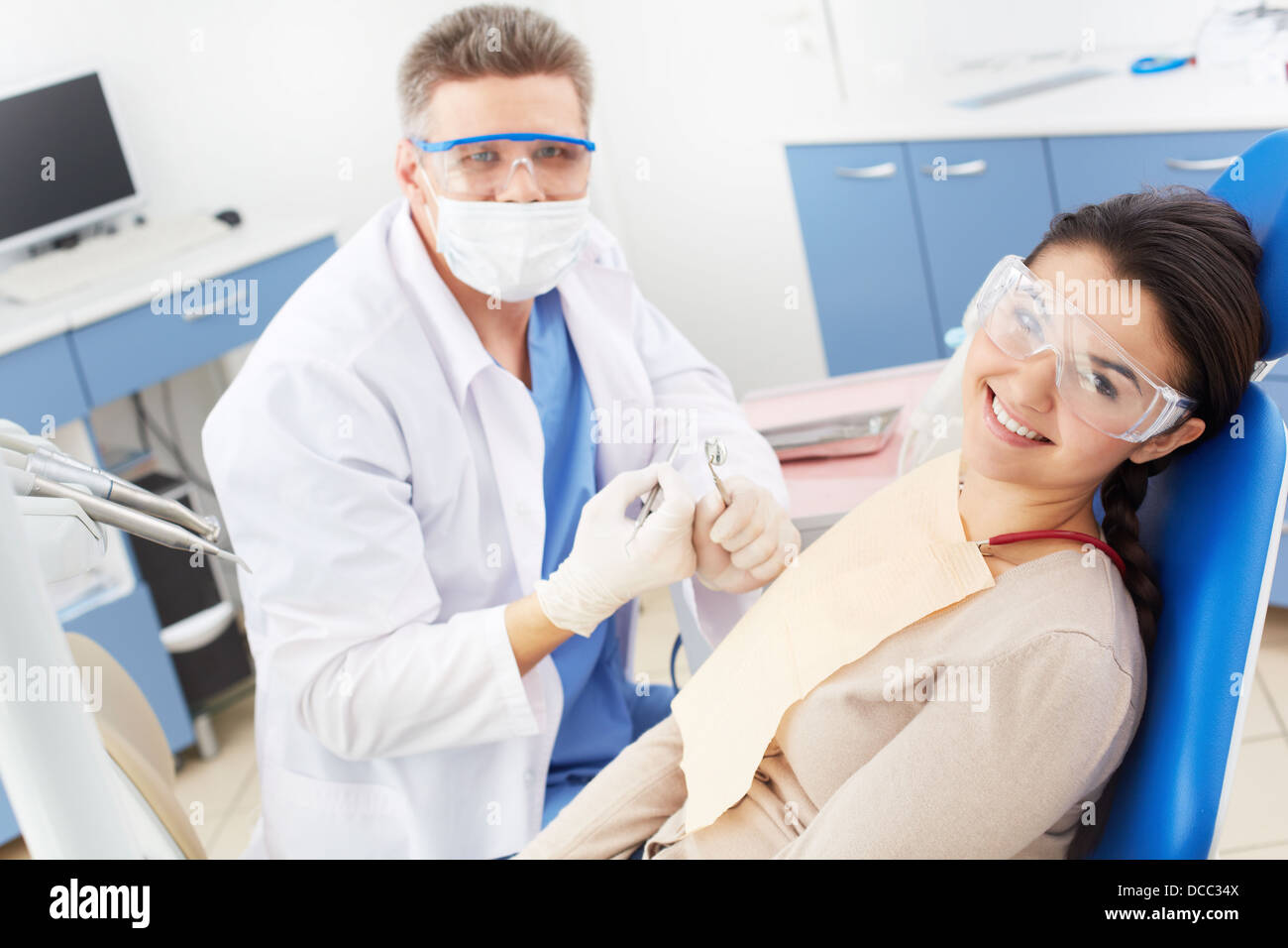 Felice la ragazza di occhiali protettivi guardando la fotocamera con sorriso toothy presso il dentista Foto Stock