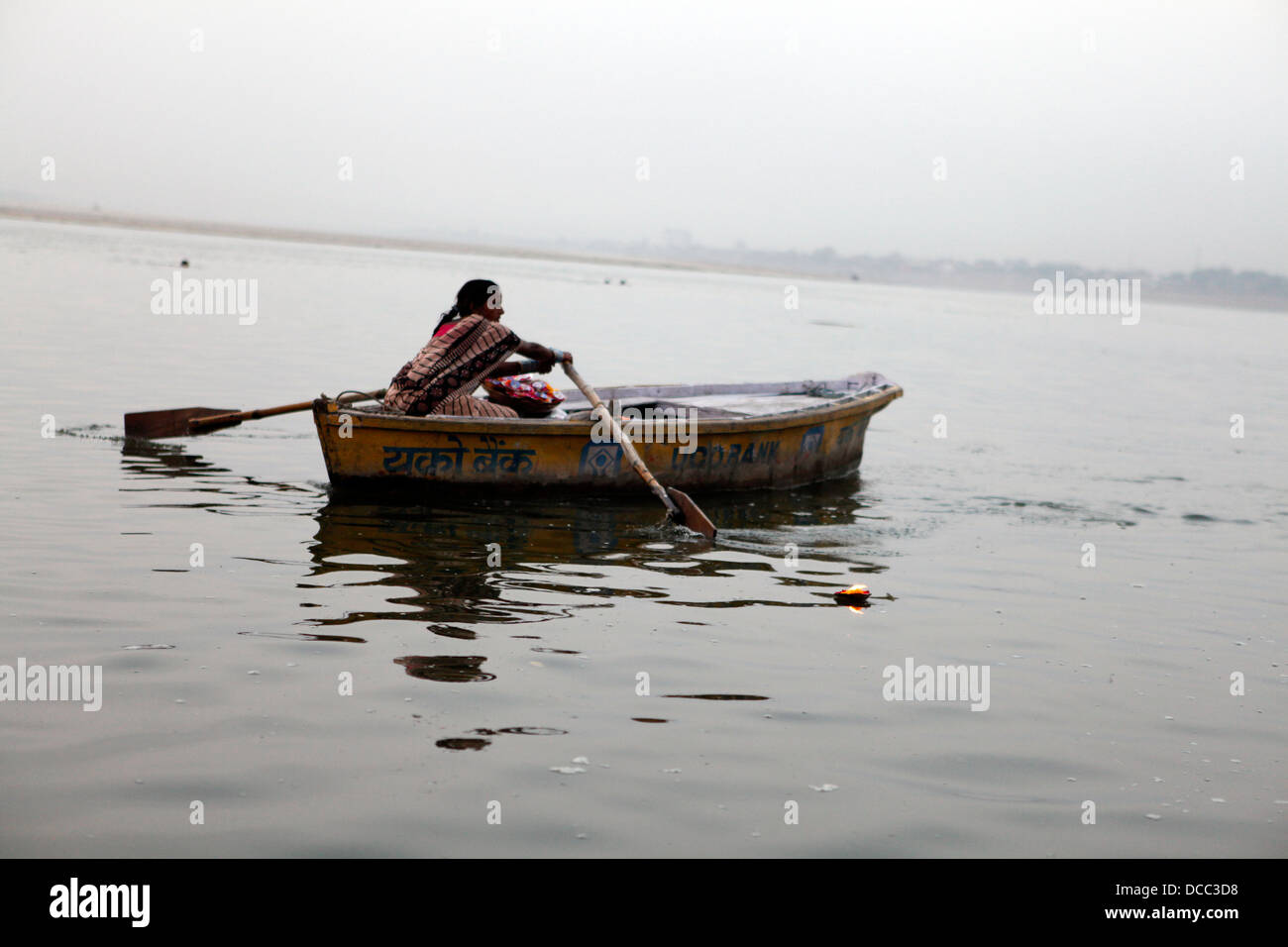 Un fiore femmina venditore righe il suo giro in barca per i turisti; Varanasi, India Foto Stock