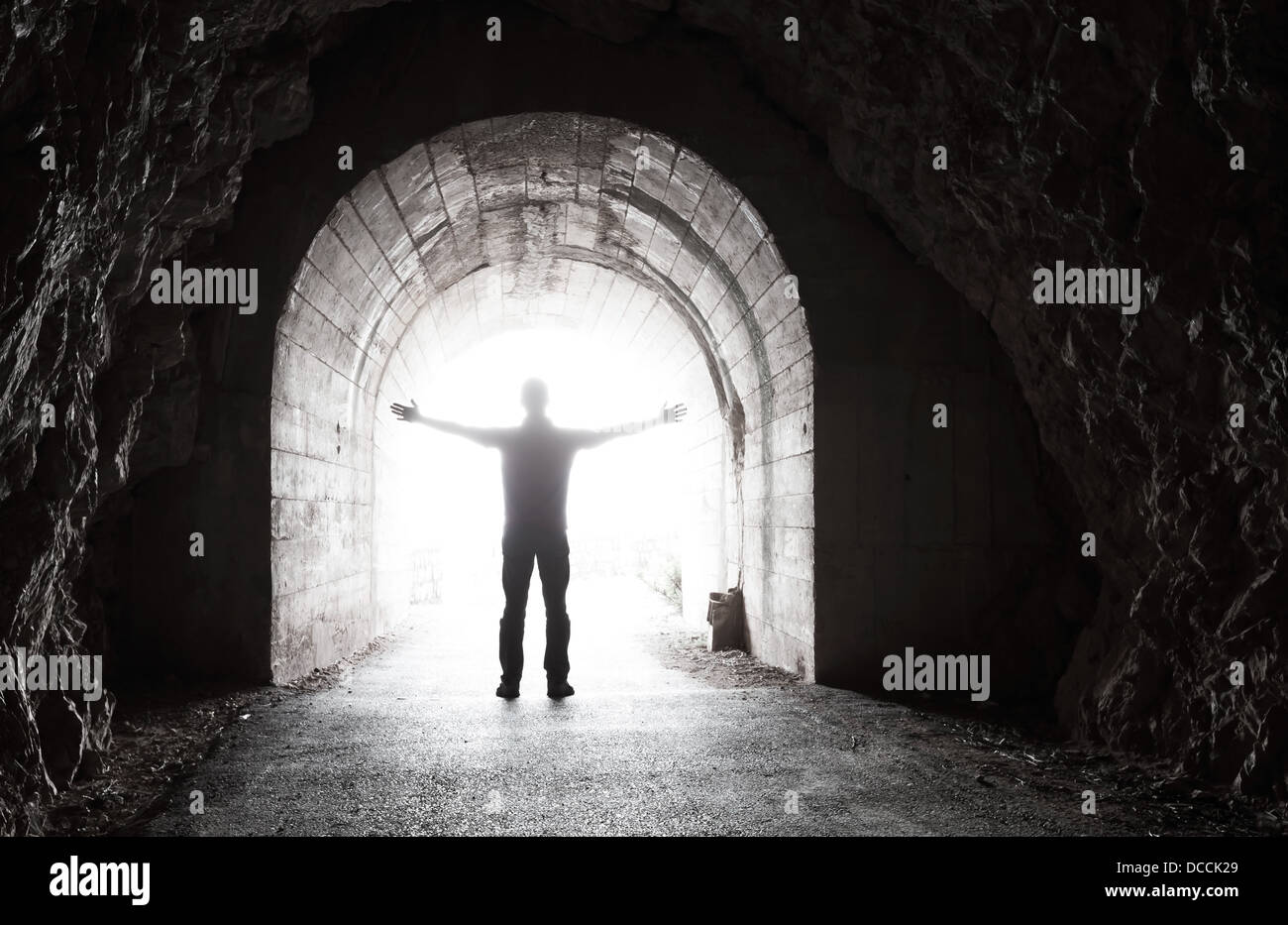 L uomo sta nel buio del tunnel con estremità incandescente Foto Stock