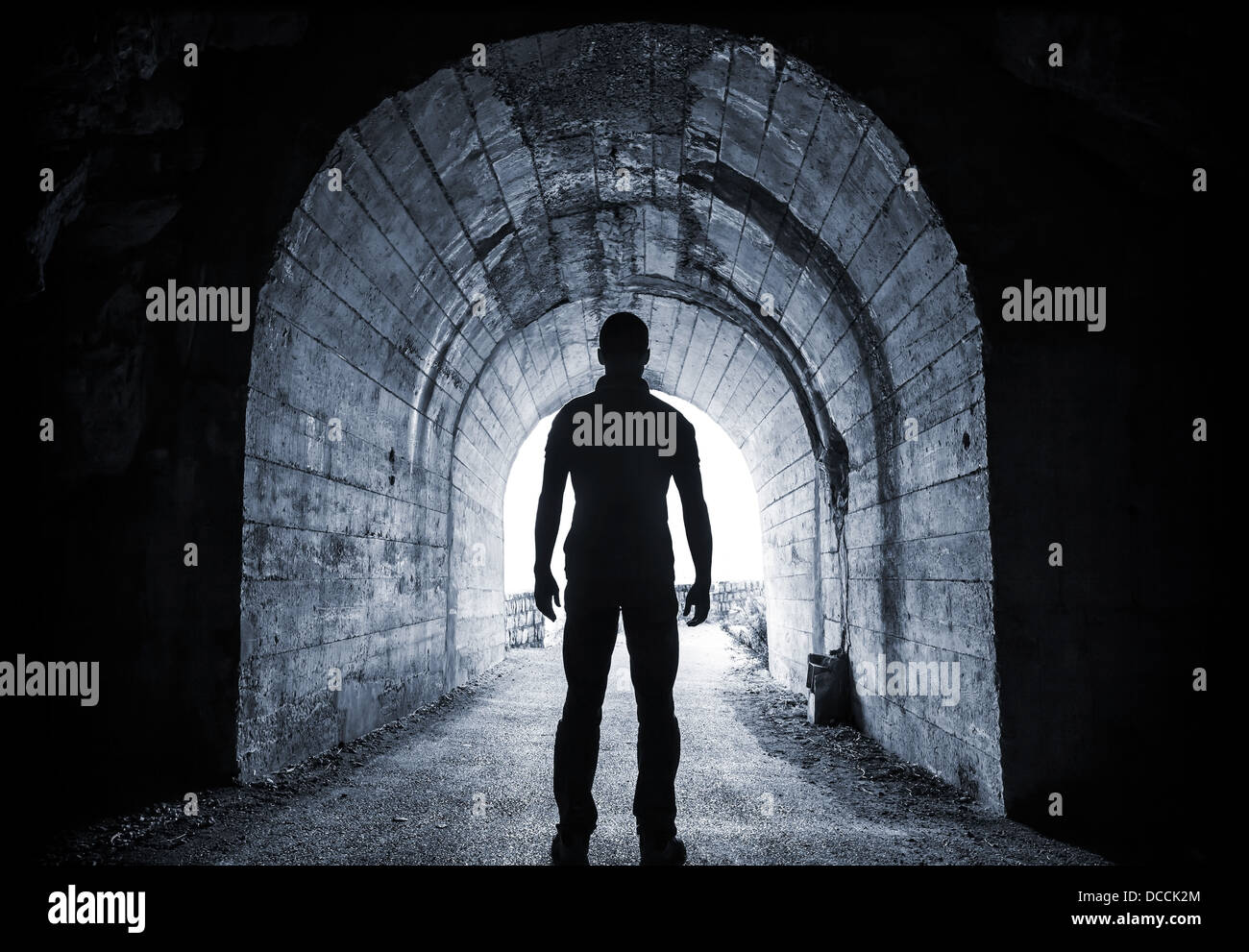 Giovane uomo sorge nel buio del tunnel e appare nel finale incandescente Foto Stock