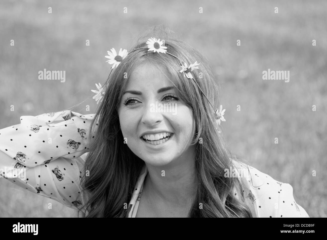 Orizzontale, immagine in bianco e nero di un felice, sorridente giovane donna con una catena a margherita nei suoi capelli Foto Stock