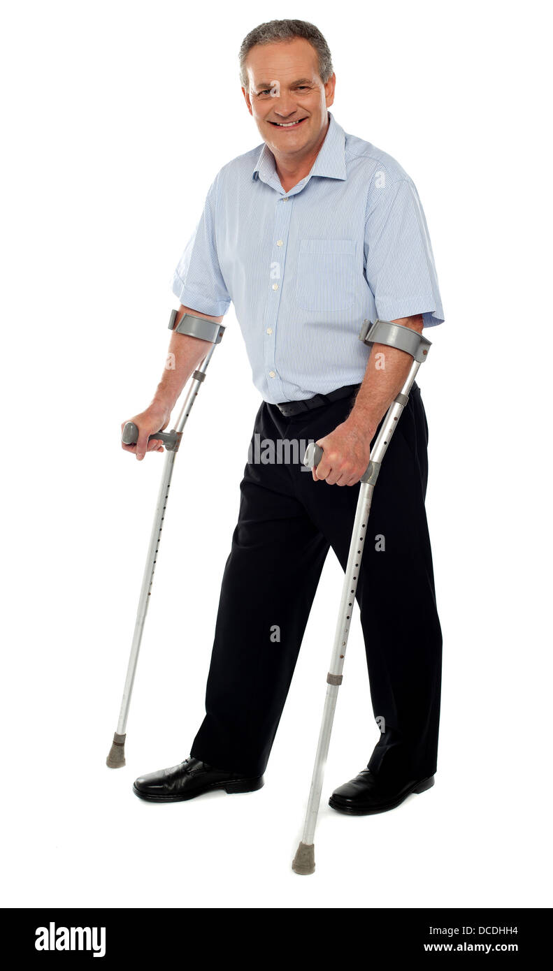 Senior man standing con l aiuto di stampelle. Ripristino da un incidente Foto Stock