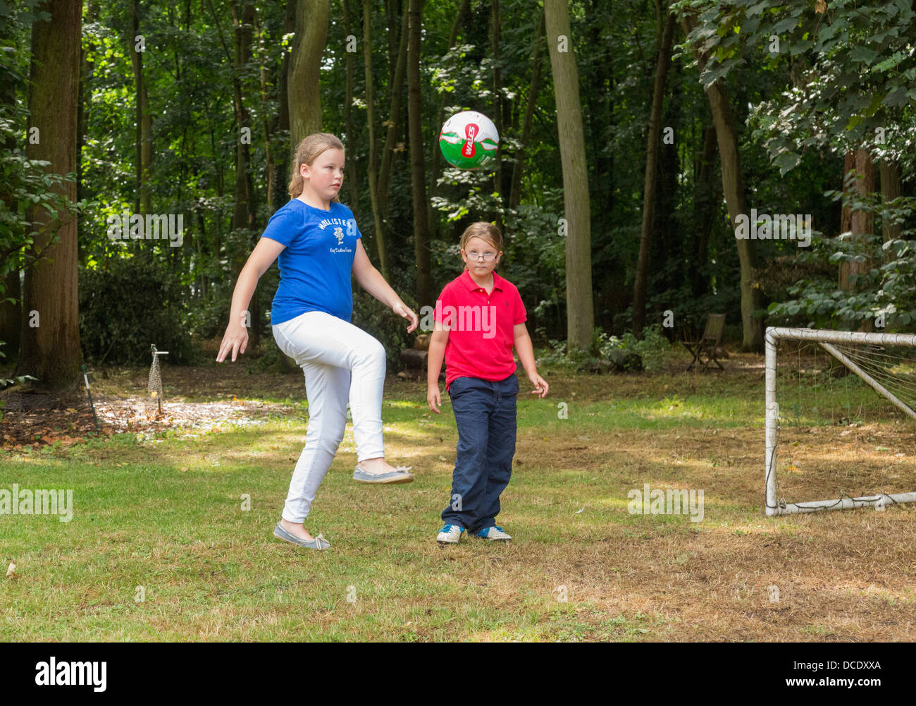 Due giovani ragazze che giocano a calcio nel cortile/giardino Foto Stock