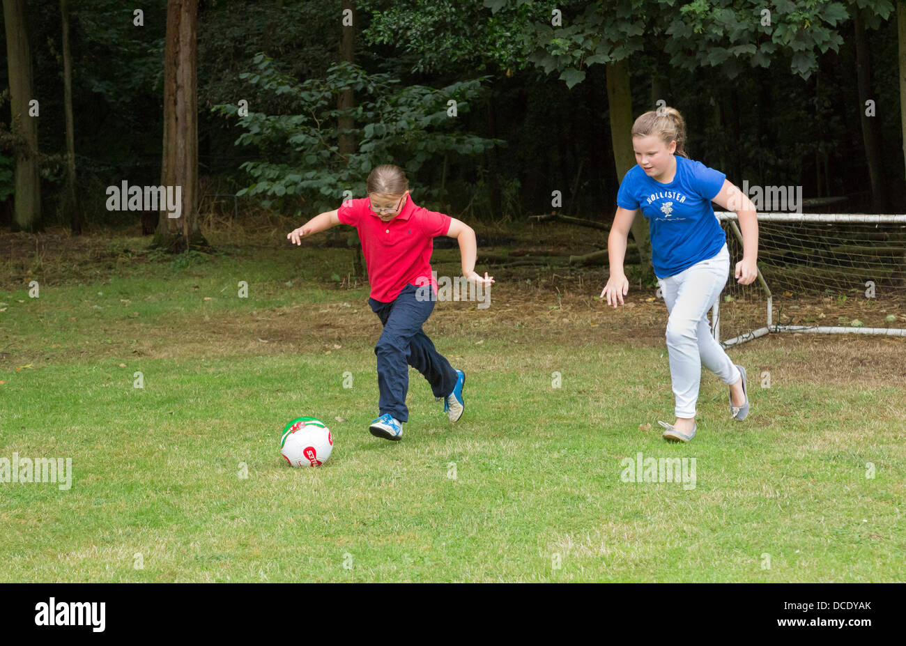 Due giovani ragazze che giocano a calcio nel cortile/giardino Foto Stock