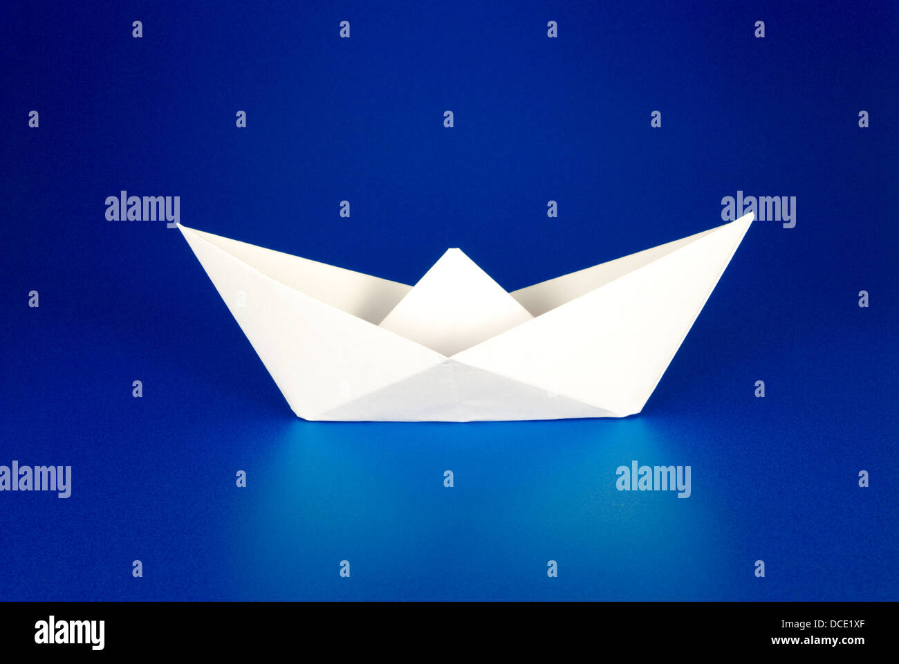Barca di carta su sfondo blu Foto Stock