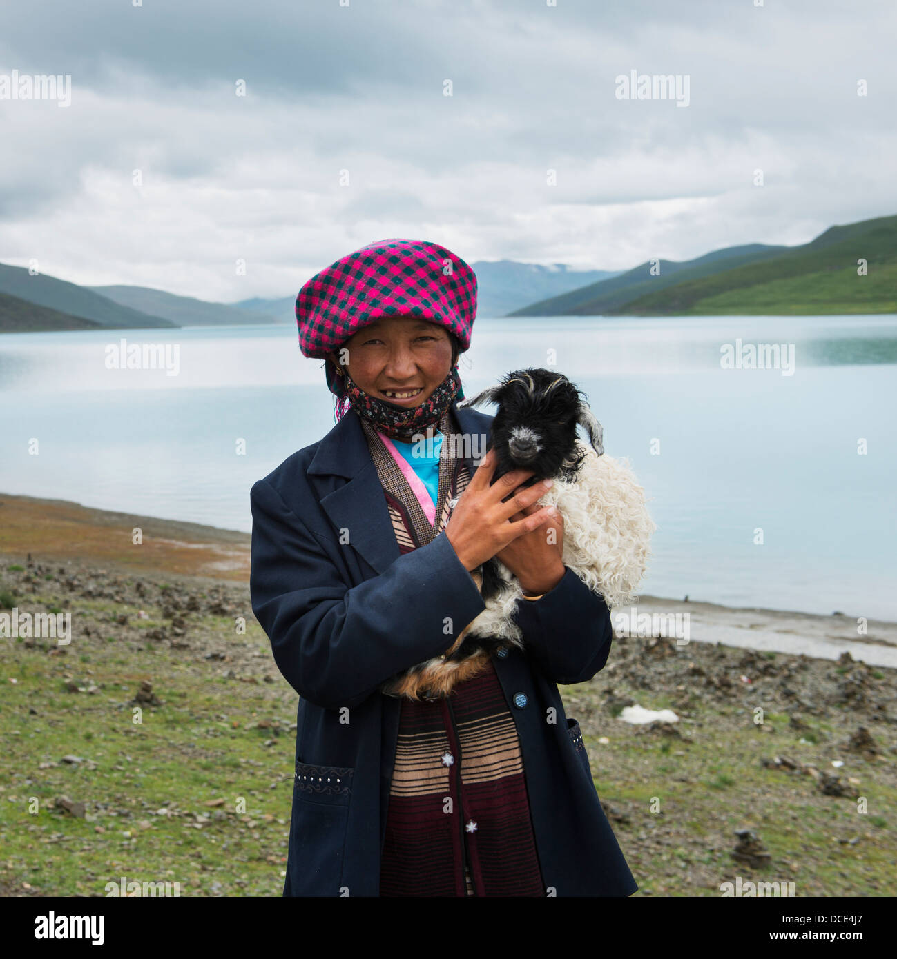 Cina, Xizang, Tibet, Shannan, donna holding, capra di piccole dimensioni sul bordo del lago sacro Foto Stock