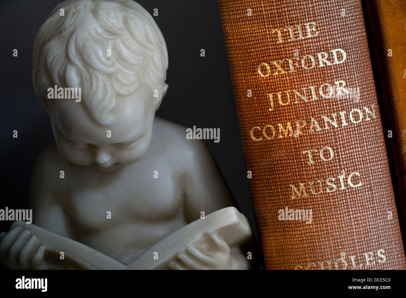 Musica libri di studio Bookend statua del giovane ragazzo lettura accanto a musica classica libro in biblioteca Foto Stock