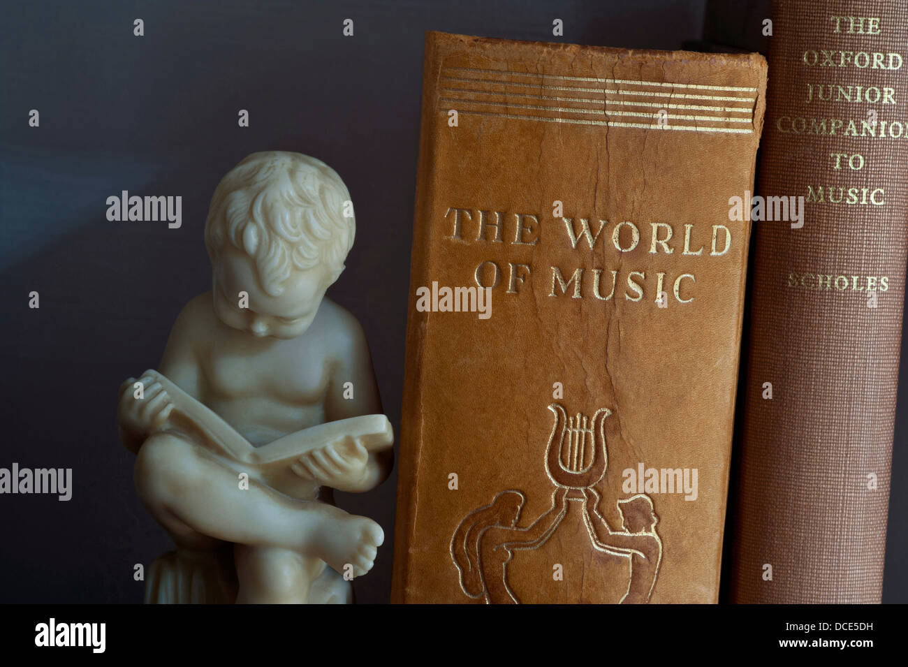 Studio musicale studiando LIBRI HOBBY INFORMAZIONI bookend scolpito statua del ragazzo lettura accanto a musica classica libri in biblioteca Foto Stock