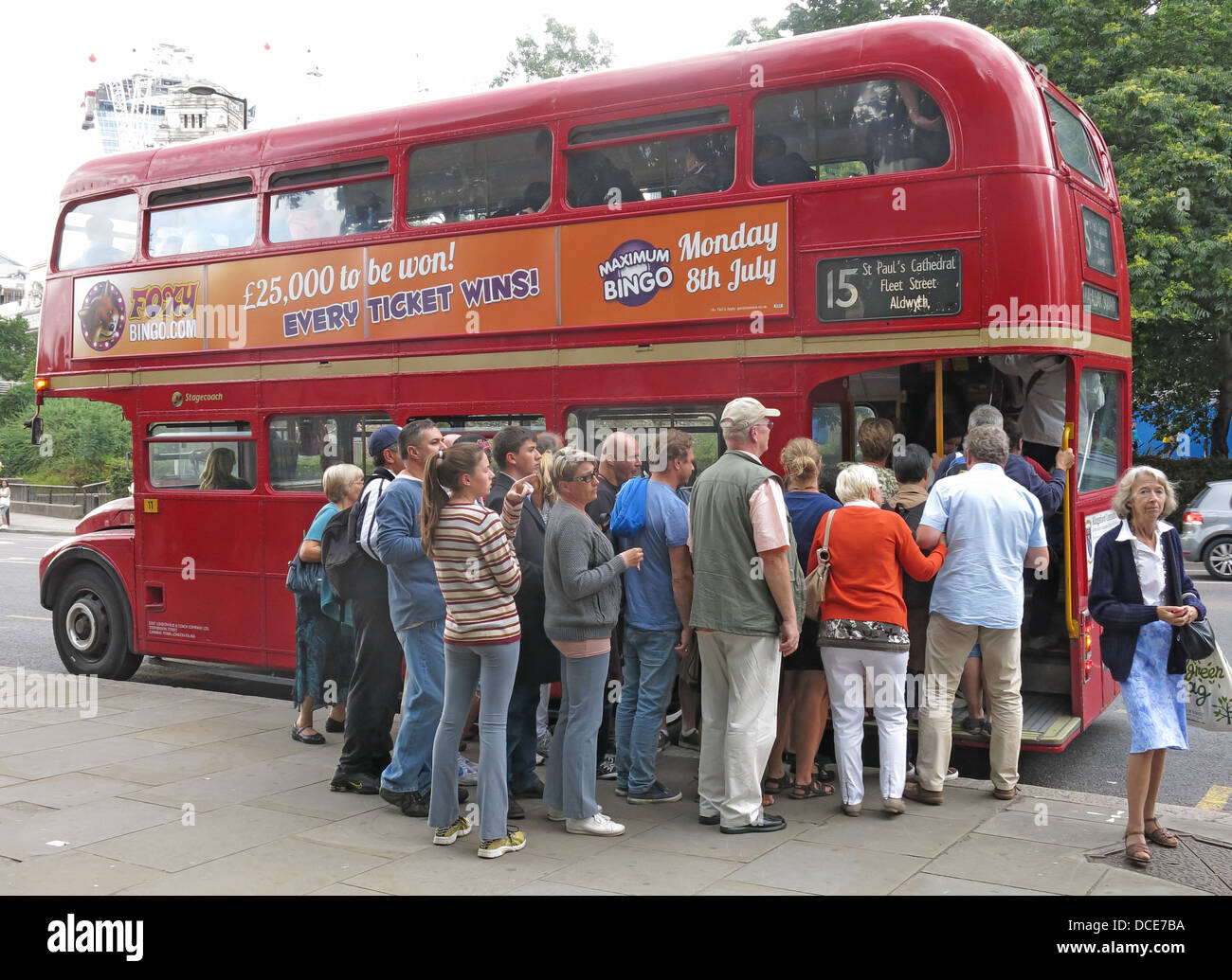 Un gruppo di turisti, in fila eccitatamente a bordo di un iconico autobus rosso London Routemaster a due piani, Classic Great Britain Foto Stock
