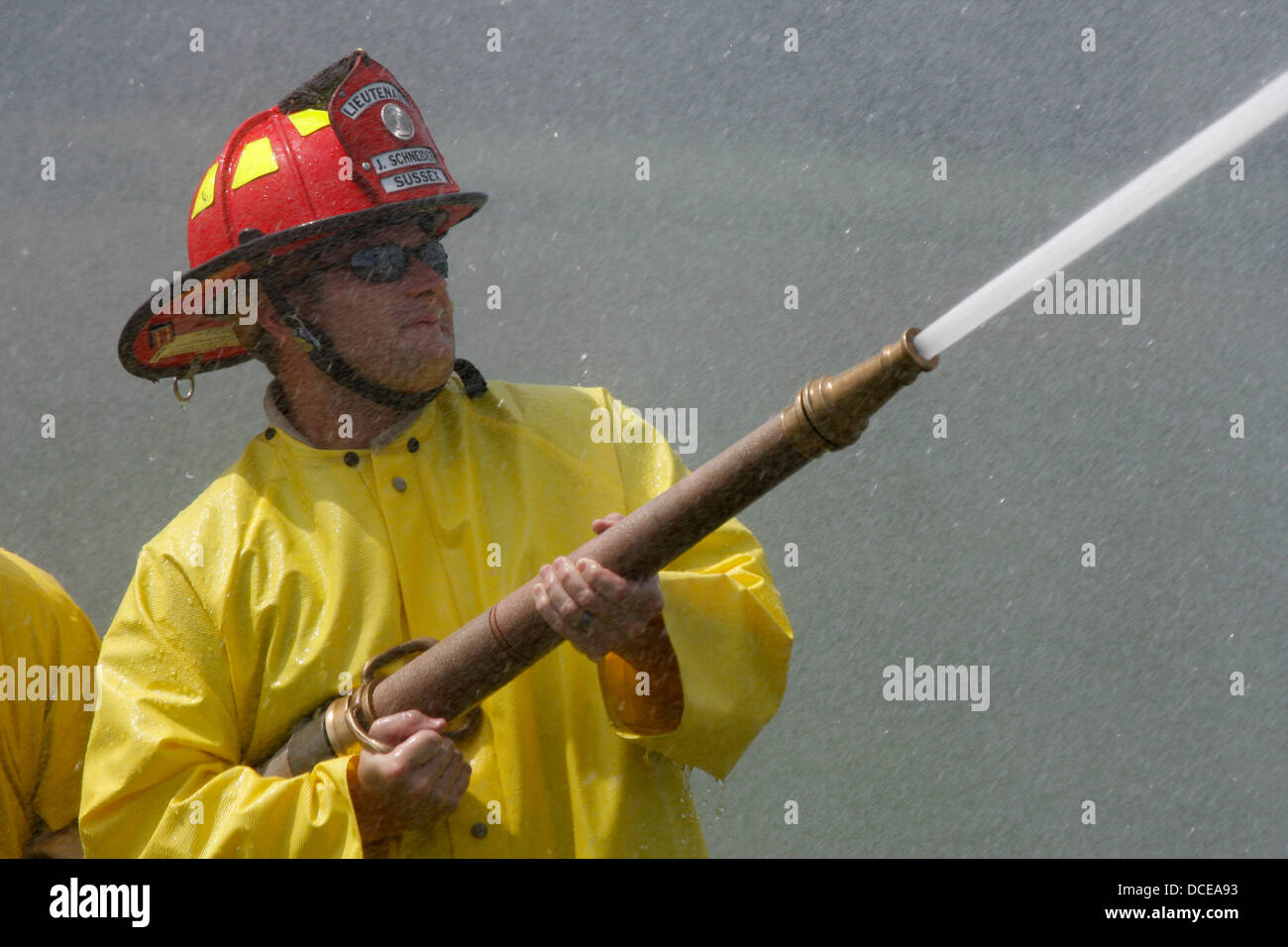 I vigili del fuoco la spruzzatura di acqua da una tubazione flessibile Foto Stock