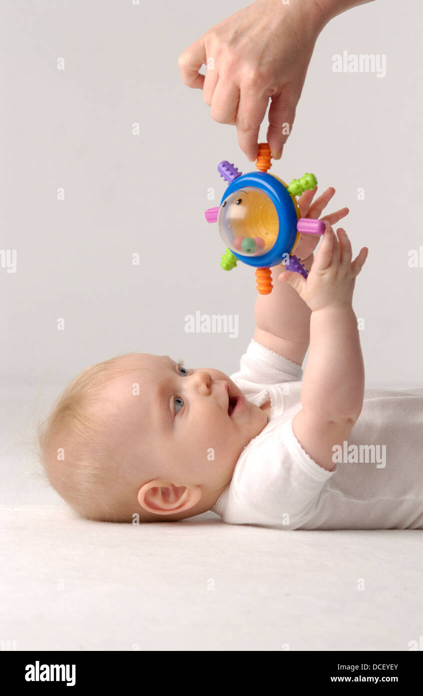 Baby girl raggiungendo per un giocattolo Foto Stock