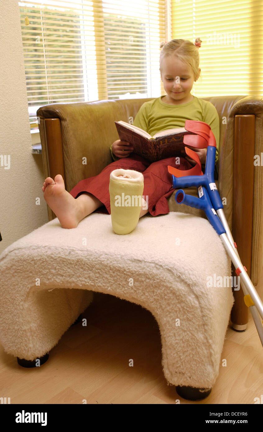 Ragazza con una gamba rotta la lettura di un libro Foto Stock