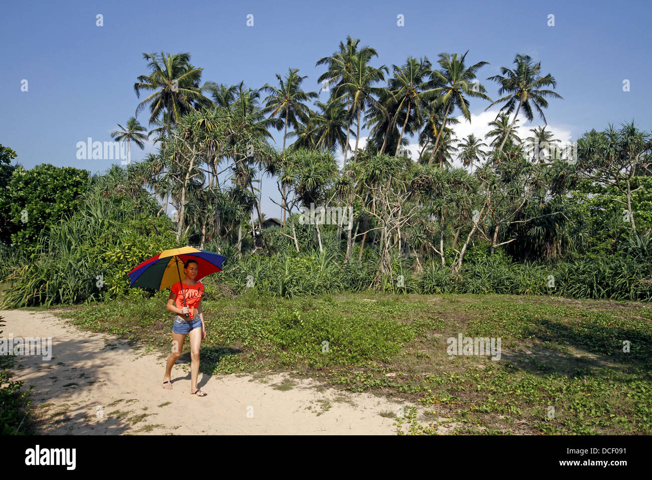 Donna che cammina con ombrellone BENTOTA SRI LANKA 13 Marzo 2013 Foto Stock