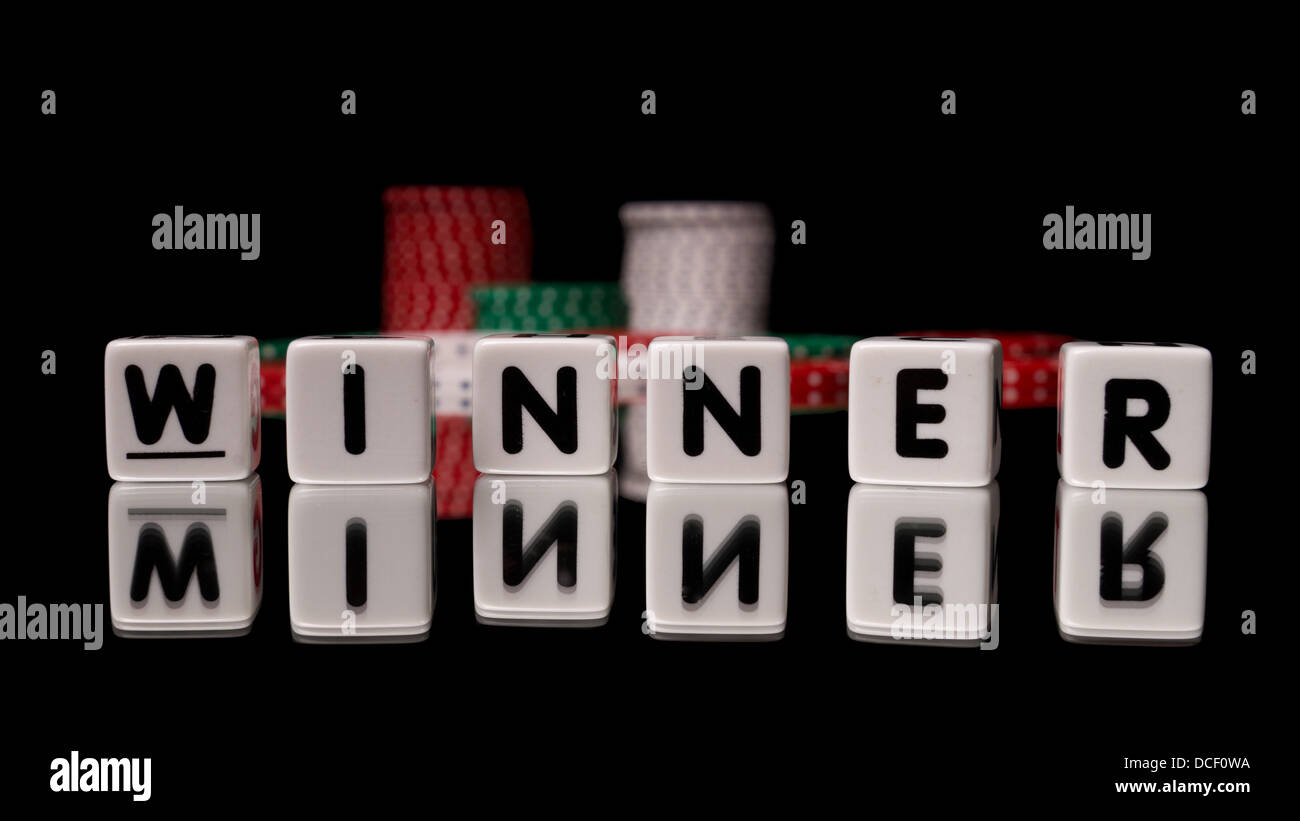 Vincitore digitato nel gioco dei dadi riflette le lettere su sfondo nero con pile di chips in background Foto Stock