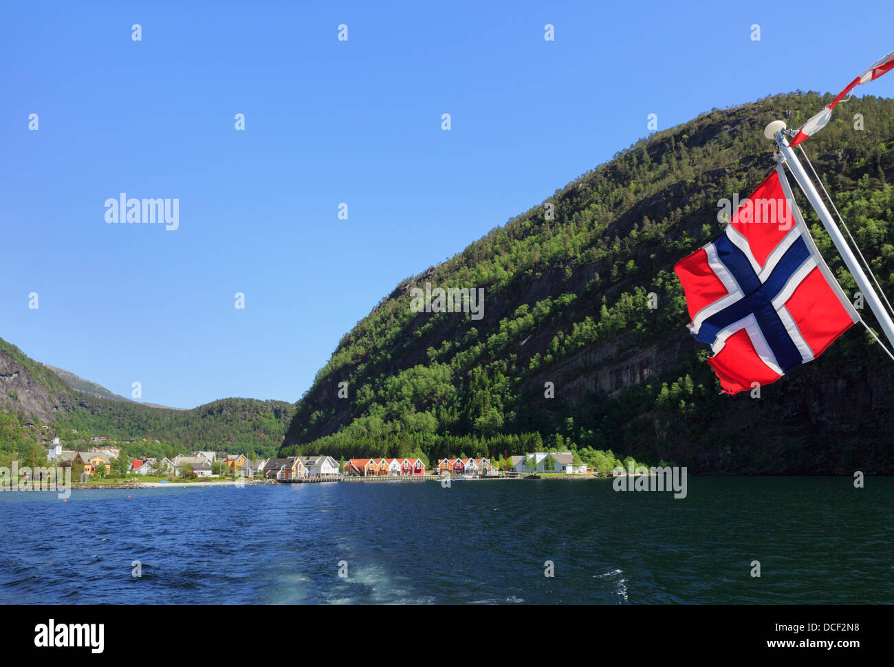 Bandiera norvegese sulla gita sulla barca Mofjorden lasciando il grazioso villaggio di Mo, Modalen ,Hordaland, Norvegia e Scandinavia Foto Stock