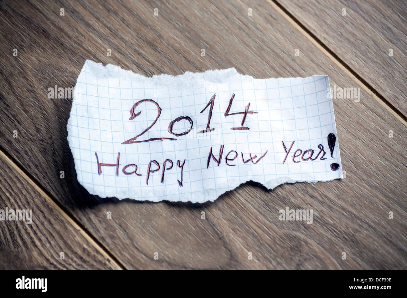 Felice anno nuovo 2014 - La scrittura a mano il testo su un pezzo di carta su uno sfondo di legno Foto Stock