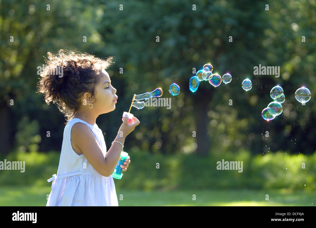 Bambina soffiare bolle nel parco Foto Stock