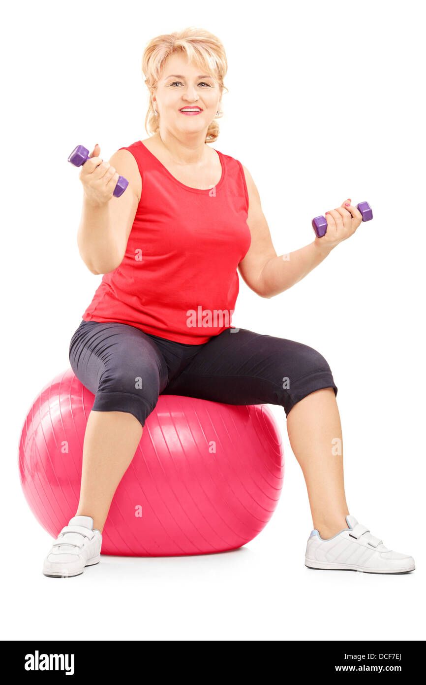 Bionda matura donna seduta su una sfera di fitness e di esercitare con manubri Foto Stock