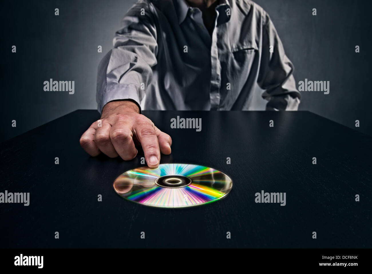L'uomo spingendo un CD con i dati in una tabella, che simboleggiano il passaggio dei dati segreti. Foto Stock