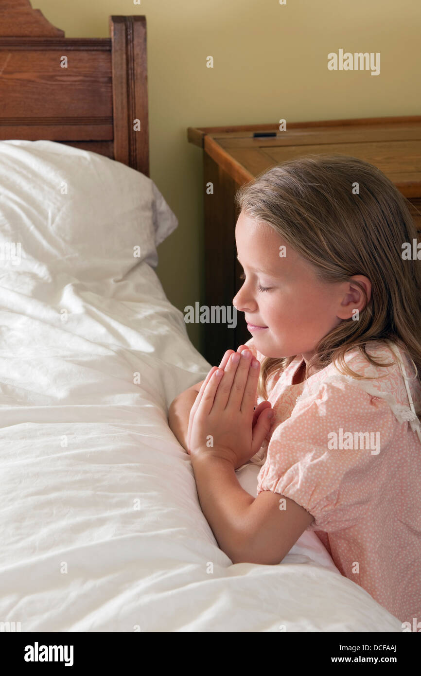 Una giovane ragazza facendo il suo coricarsi preghiere Foto Stock