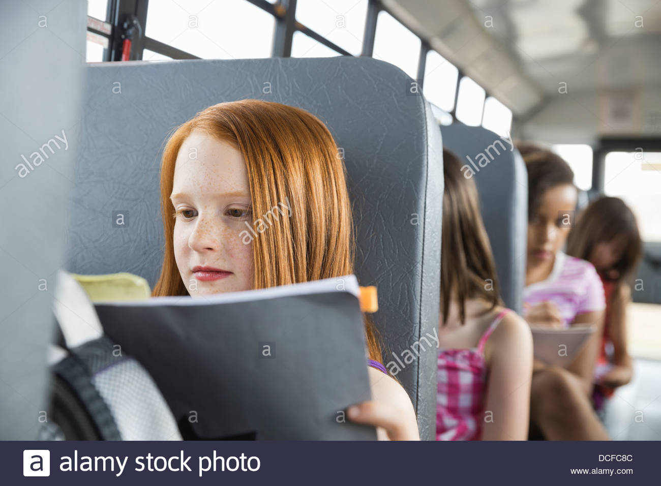La scolaretta libro di lettura sul bus Foto Stock
