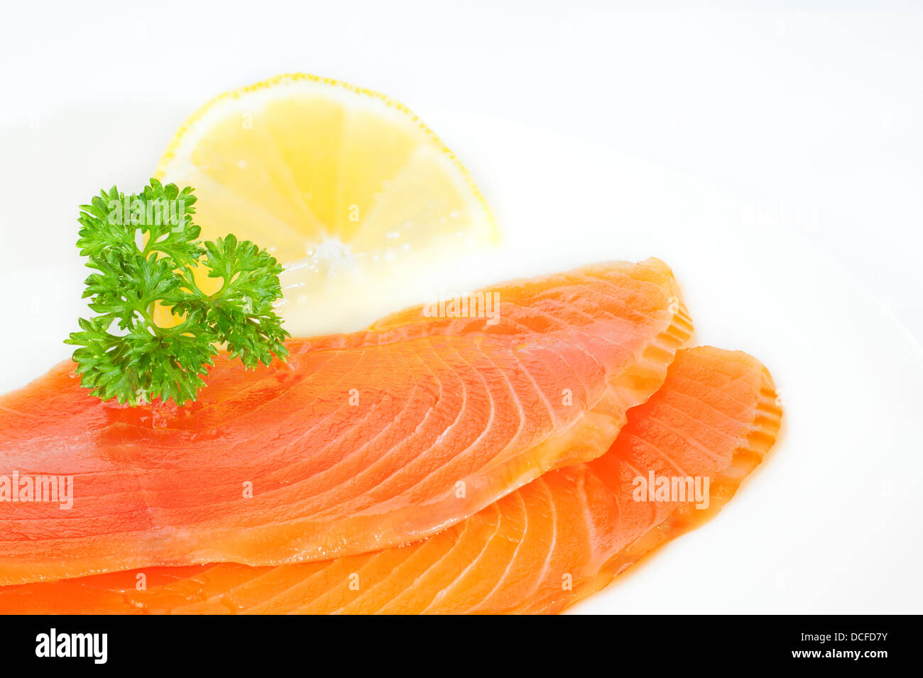 Salmone affumicato - freddo salmone affumicato su una piastra con prezzemolo e limone. Foto Stock