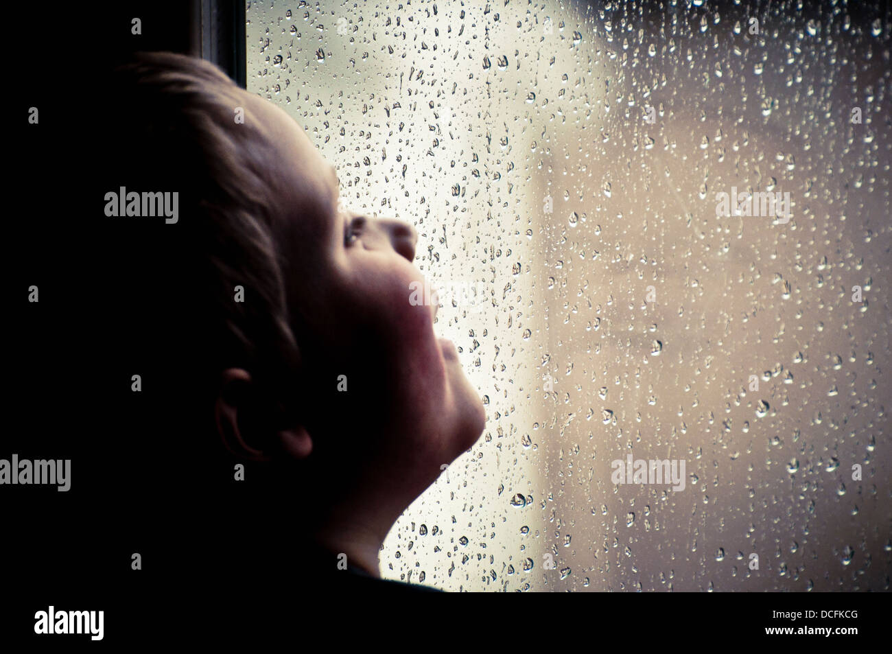 Bambino guardando la pioggia Foto Stock