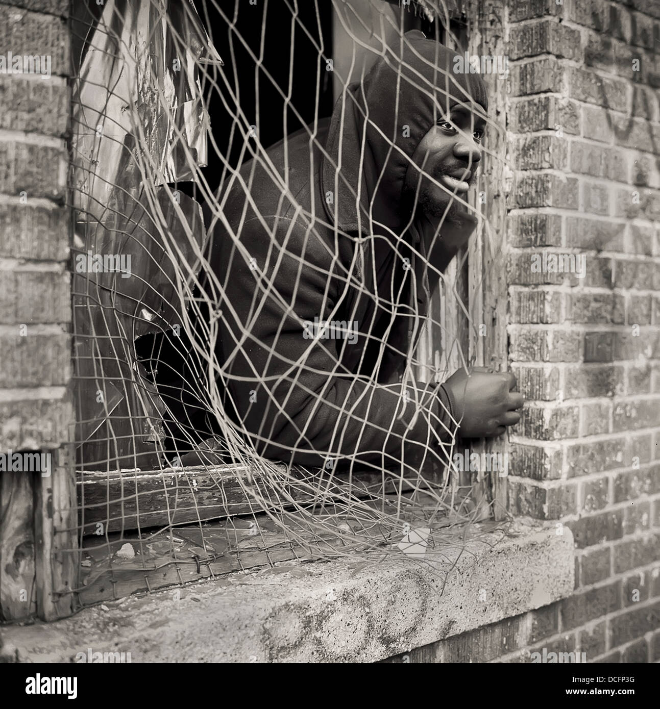Uomo senza tetto nel Bronx, New York City si appoggia sul davanzale della finestra di un edificio abbandonato. Foto Stock