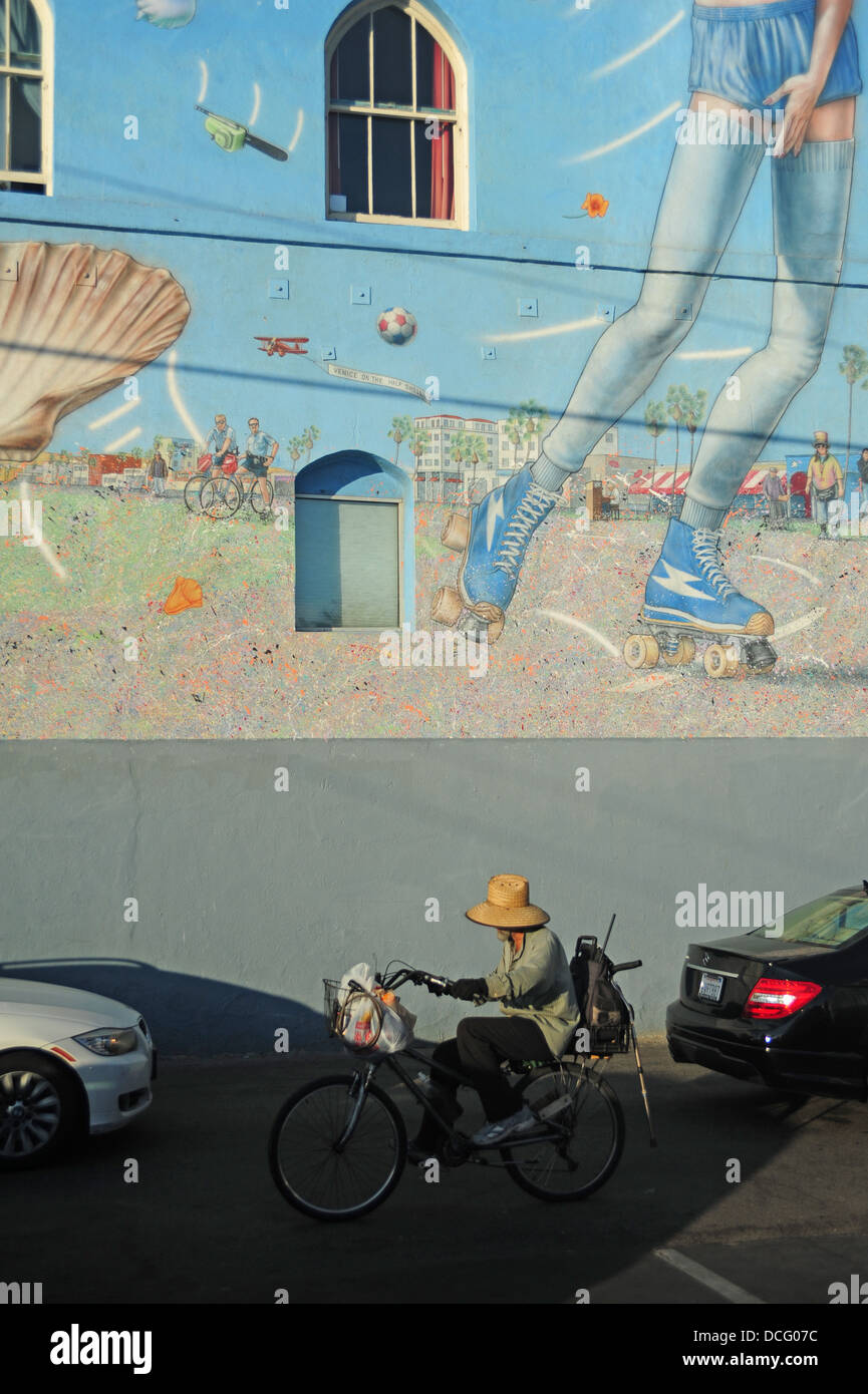 Stati Uniti d'America California CA Los Angeles L.A. LA SPIAGGIA DI VENEZIA uomo su una bicicletta cicli passato un grande murale Foto Stock