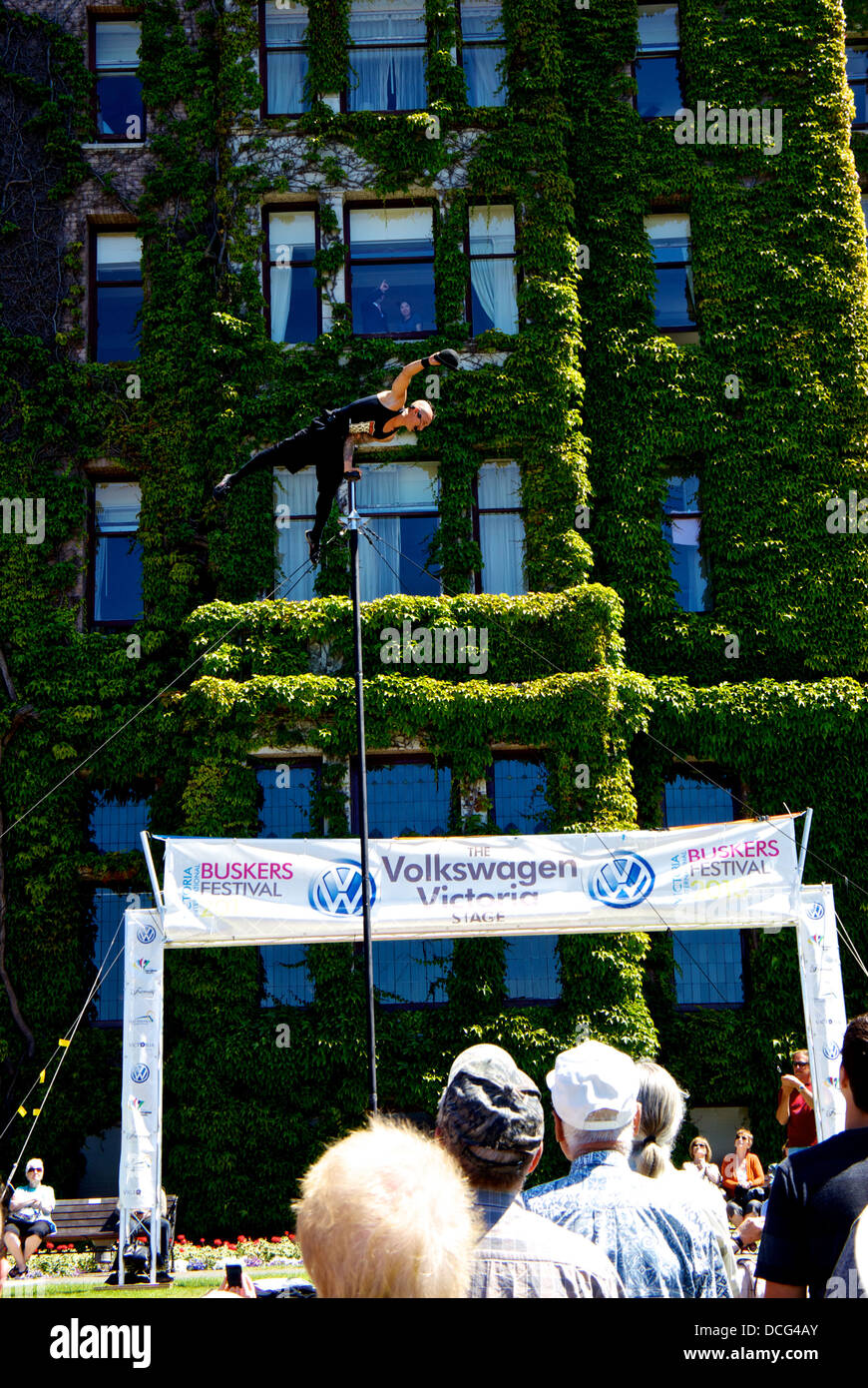 Victoria international buskers festival performer con una sola mano atto di bilanciamento in cima al palo alto Fairmont Empress Hotel motivi Foto Stock