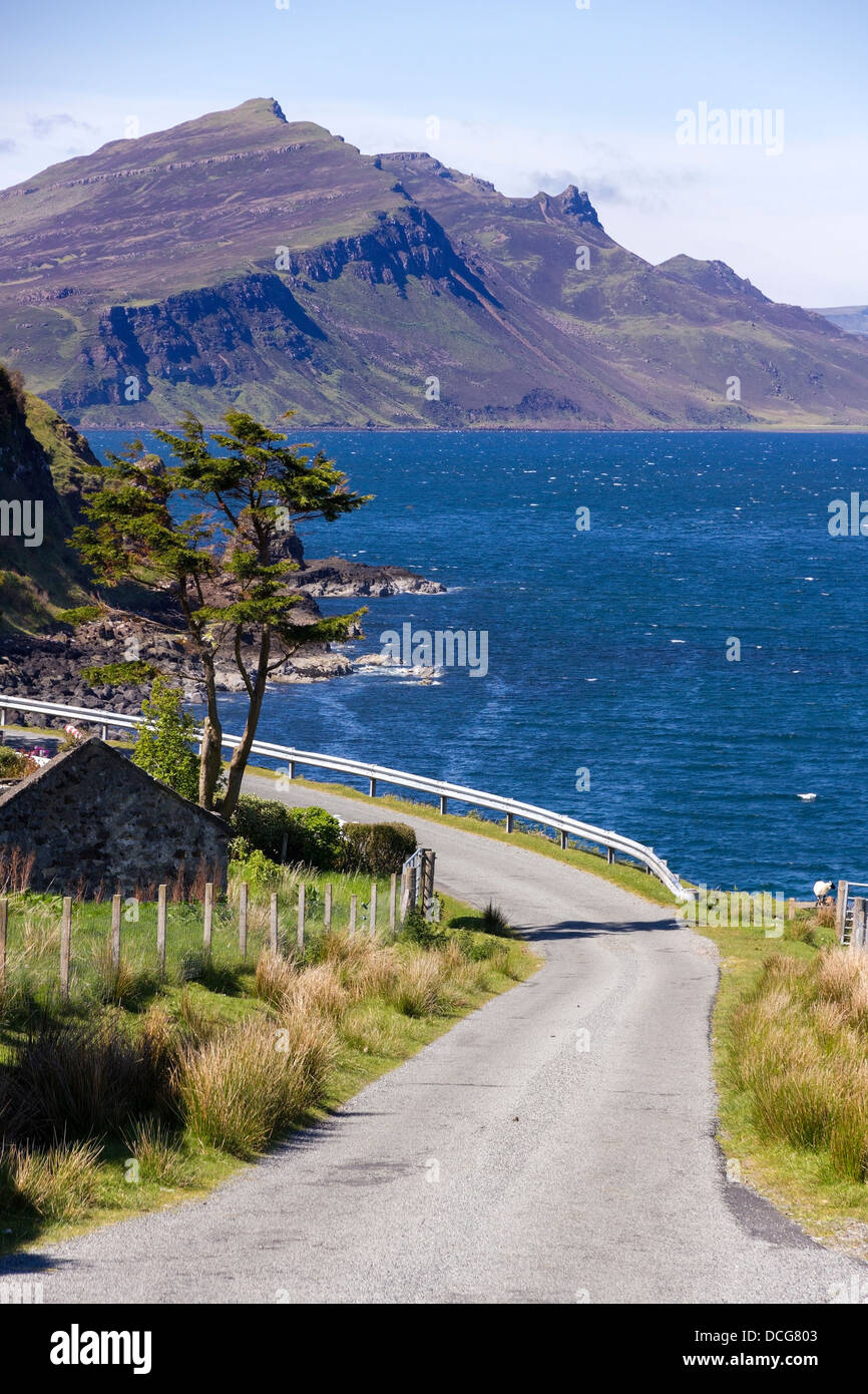 Stretta strada costiera con il mare e le montagne del Trotternish Ridge al di là di come si vede dal bricchi, Isola di Skye, Scotland, Regno Unito Foto Stock